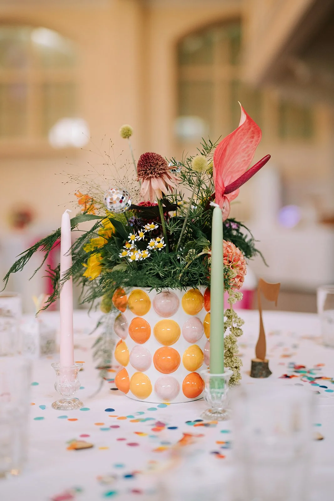 Colourful wedding flower centrepiece in yellow and orange ball shape vase created by MillieBuds Colour Loving Wedding Florist in Stockport at Bowdon Rooms