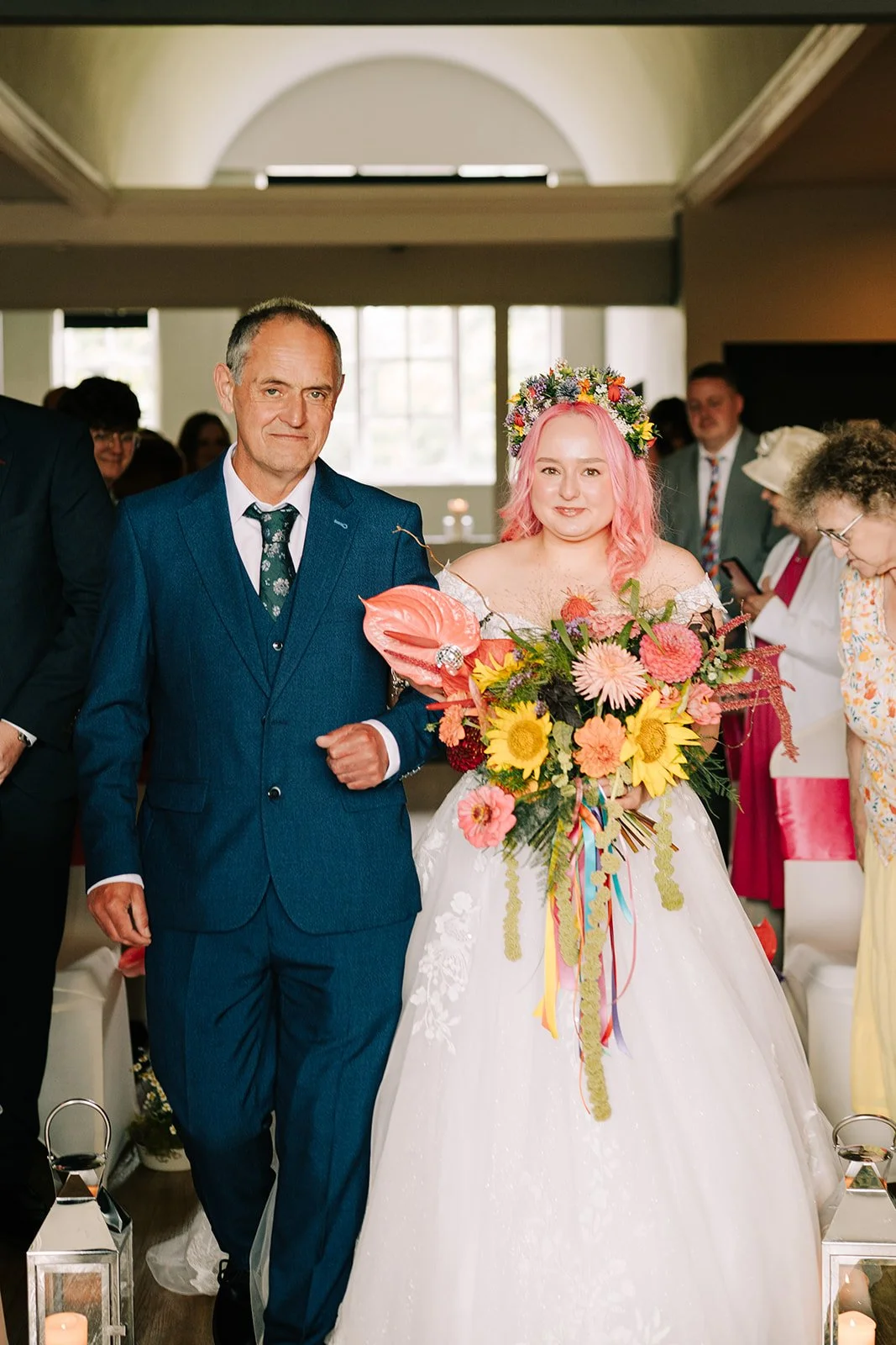 Bride and father walking down aisle with colourful bridal bouquet created by MillieBuds Colour Loving Wedding Florist in Stockport at Bowdon Rooms