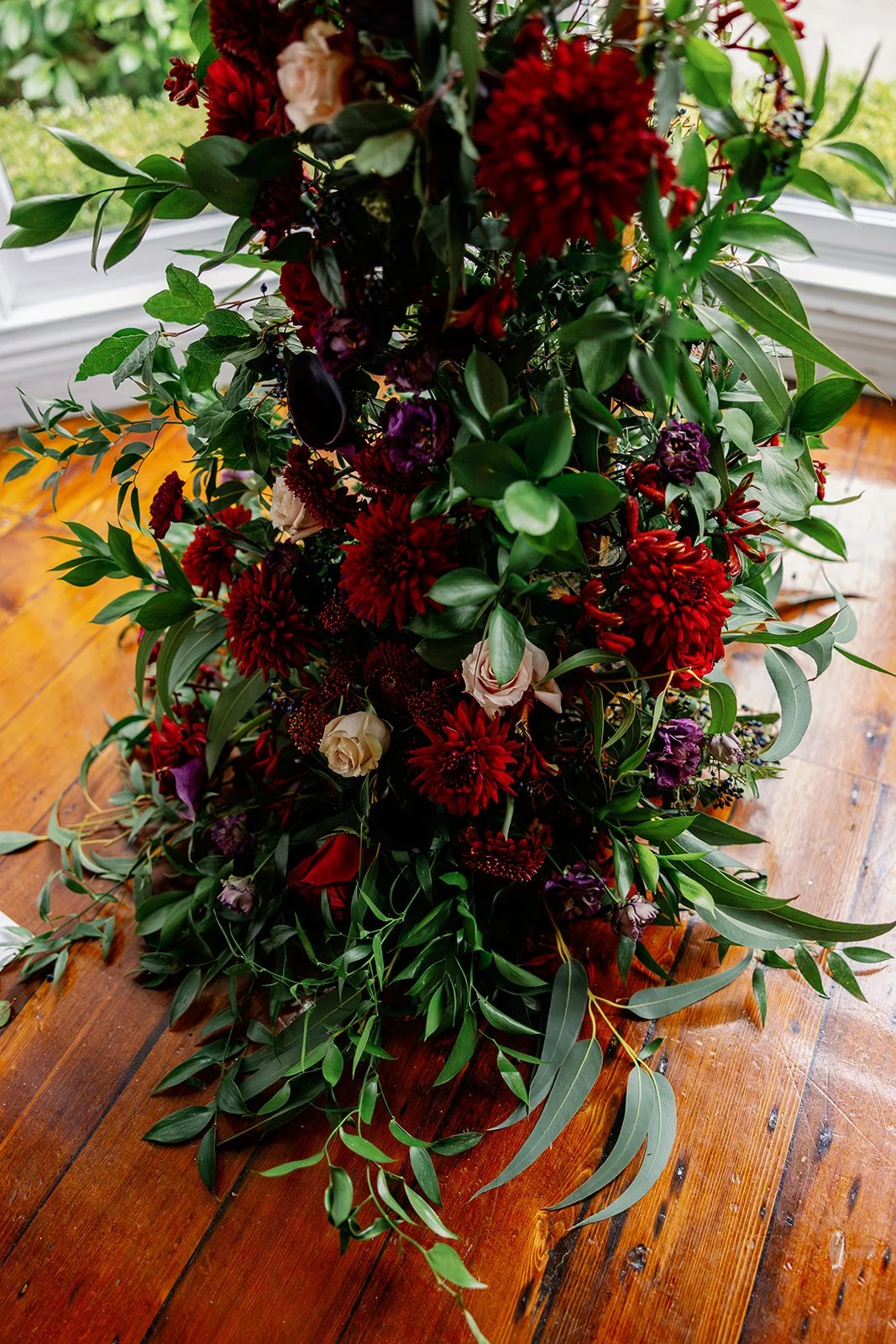 Up close of split arch, moody red wedding flowers