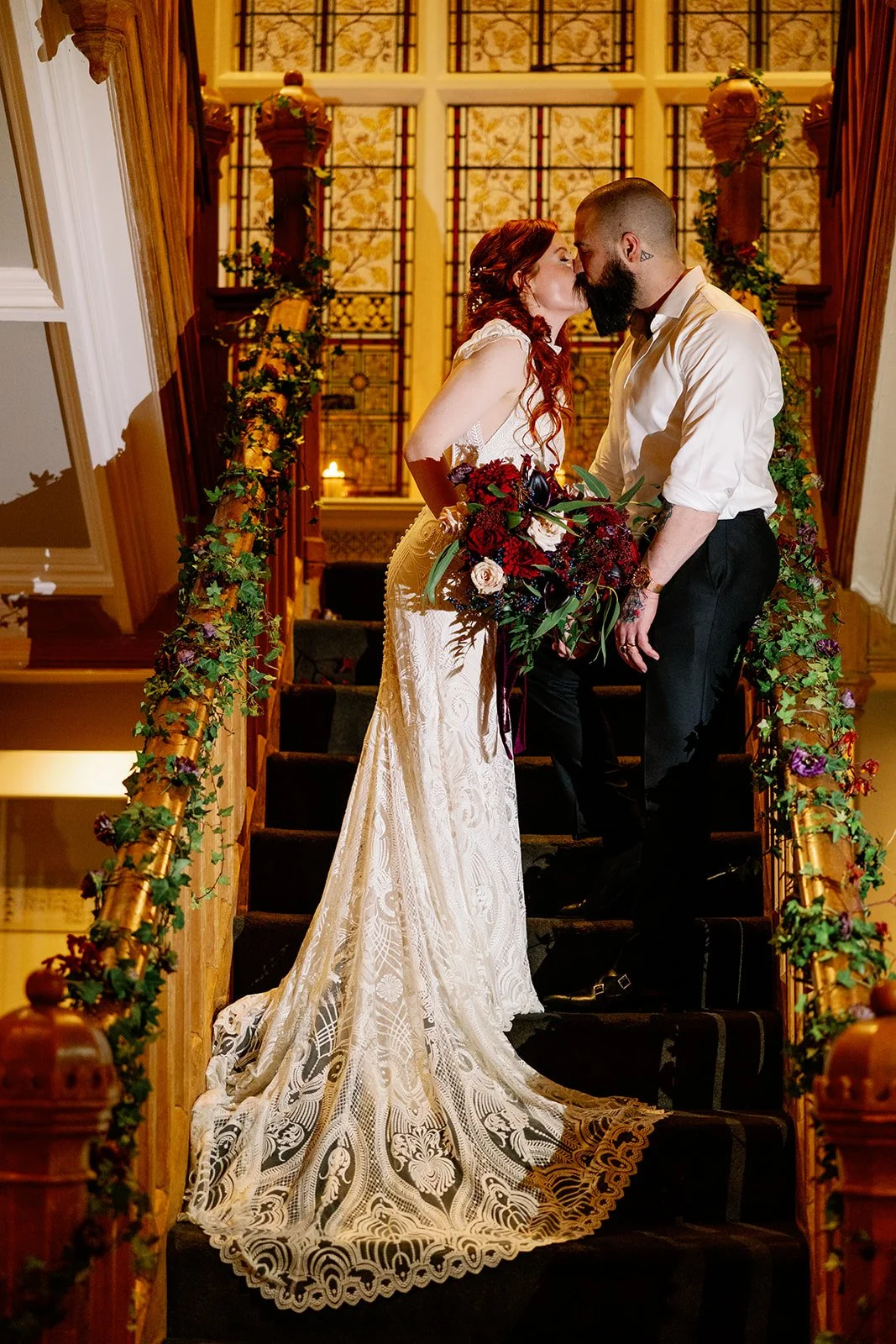 Moody red wedding flowers couple kissing on stairs