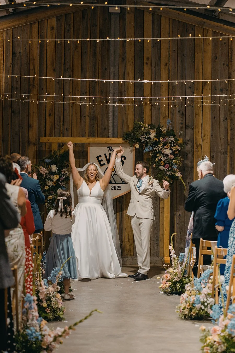 Bride & groom just married in front of colourful flower arch created my MillieBuds Wedding Florist