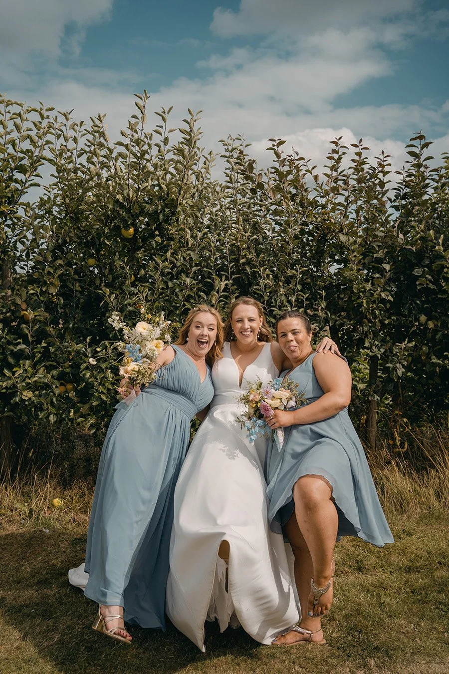 Bride and bridesmaids with white bridal bouquet and pastel bridesmaid bouquets, created by MillieBuds Wedding Florist Stockport