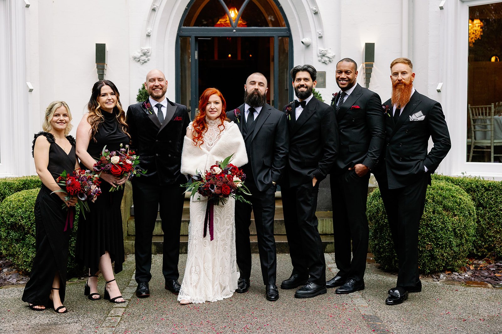 Wedding party posing with moody red and purple abundant flower bouquets and buttonholes created by MillieBuds Wedding Florist, Stockport