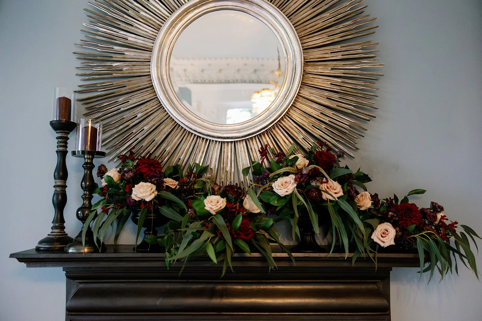 Moody red wedding flowers decorating dark firepalce