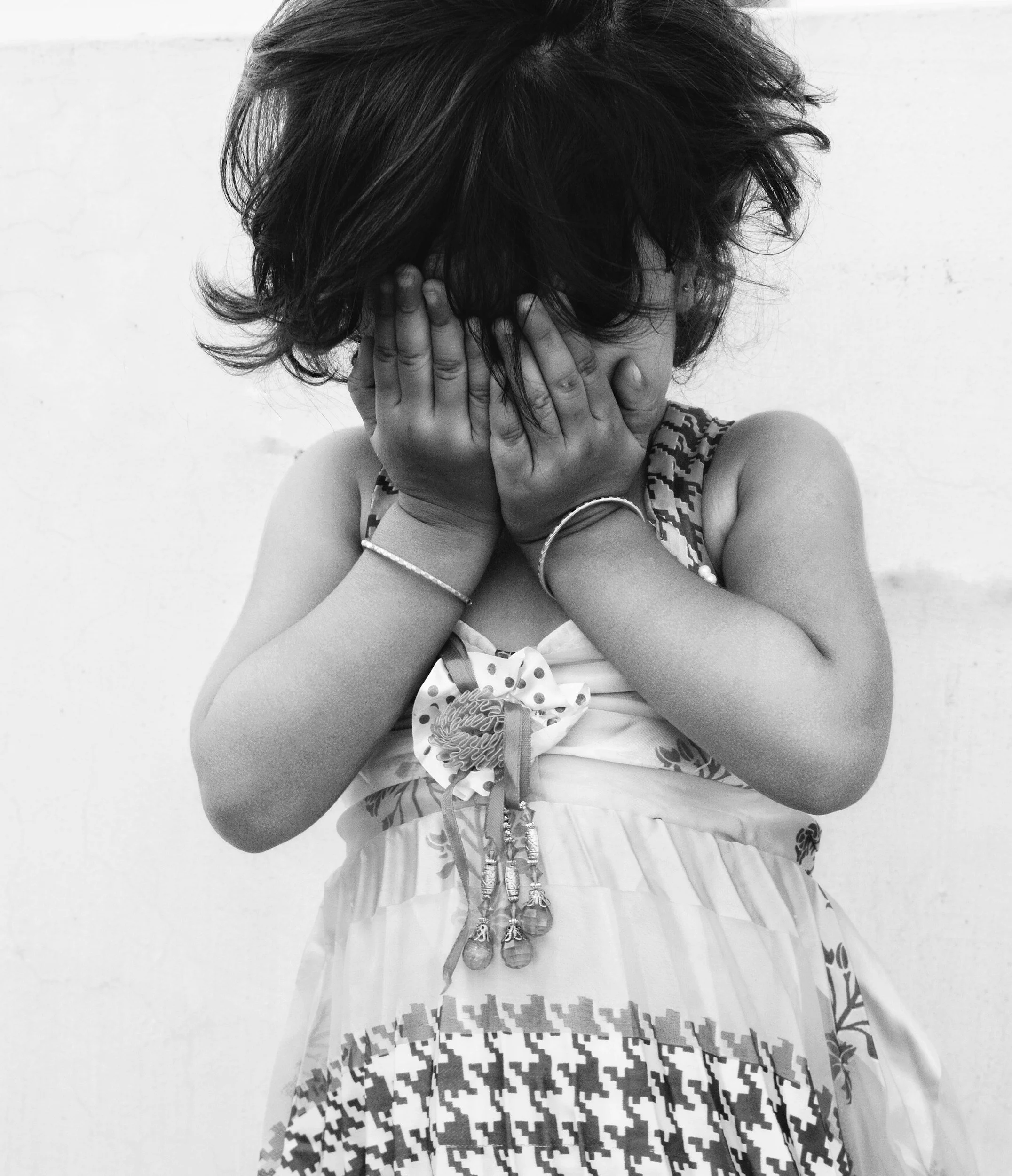 Young female child covering her face after being discouraged when she expressed her emotions