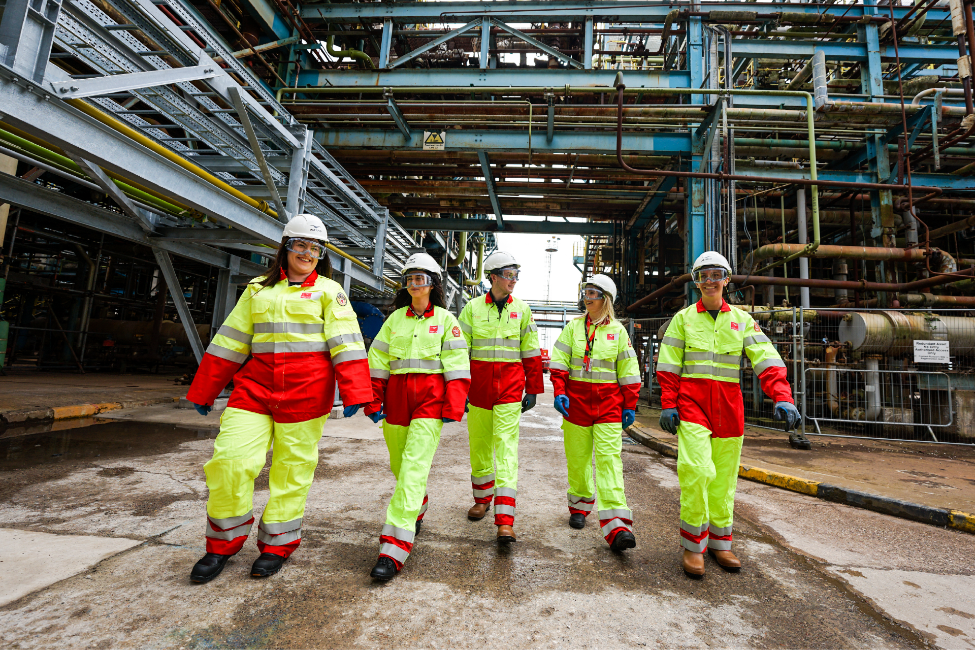Five people wearing high vis PPE on an industrial site. Specialist communications agency for infrastructure