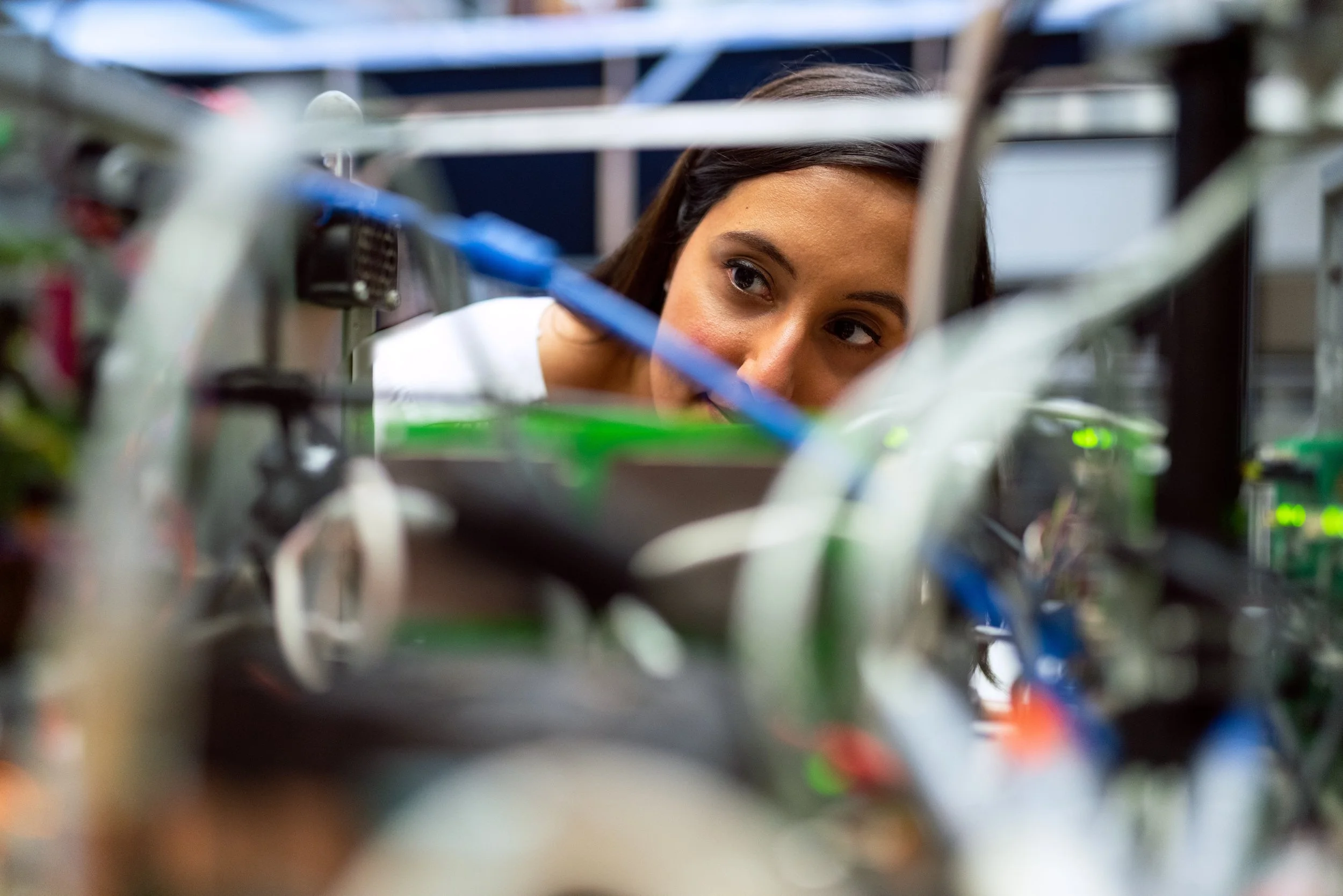 An engineer, a woman with brown hair, looks at some blue wires. Really Good Things is a specialist transformation and strategic change consultancy
