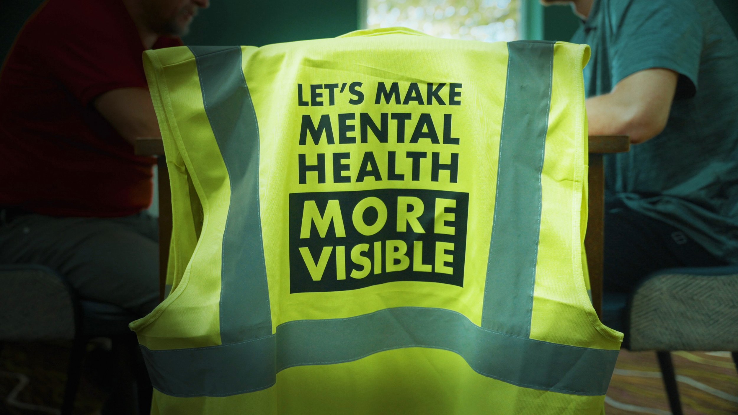 Neon yellow high vis vest that says LET'S MAKE MENTAL HEALTH MORE VISIBLE