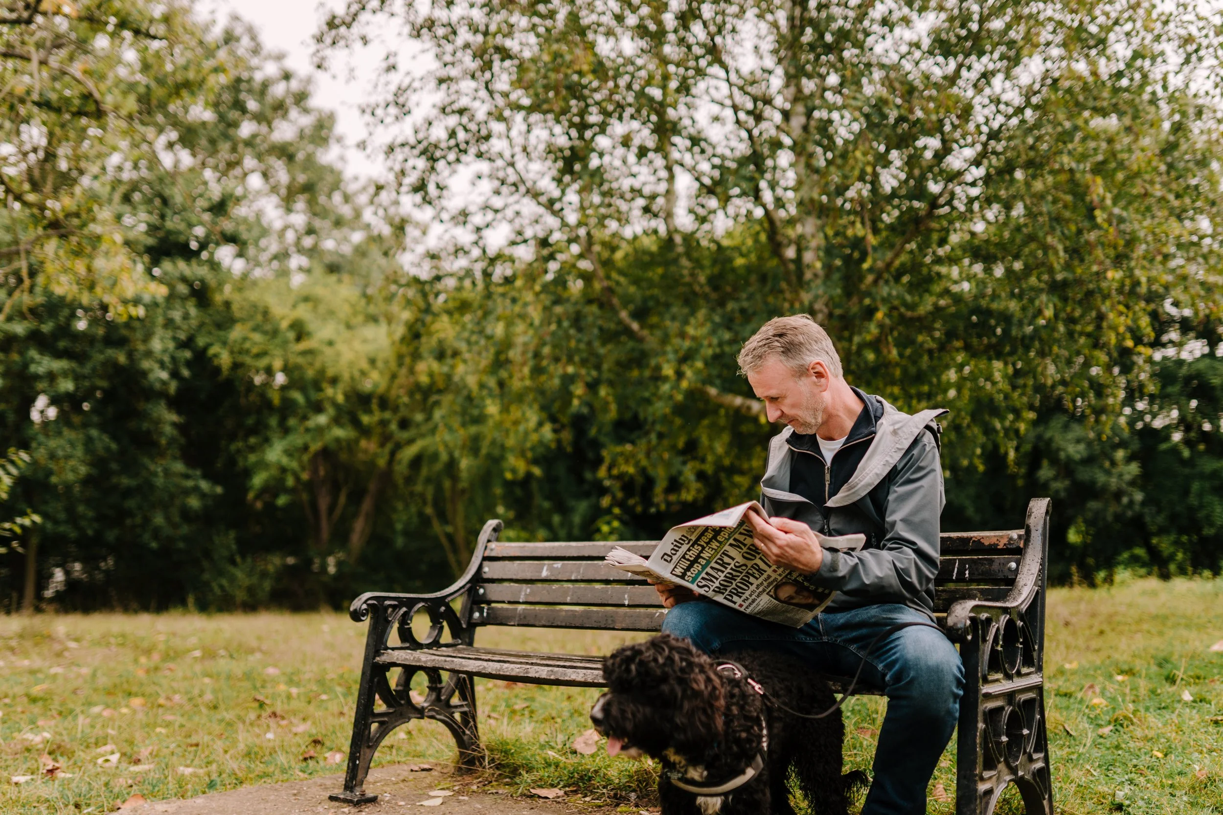 A man sits on a bench reading a paper. Community engagement consultancy