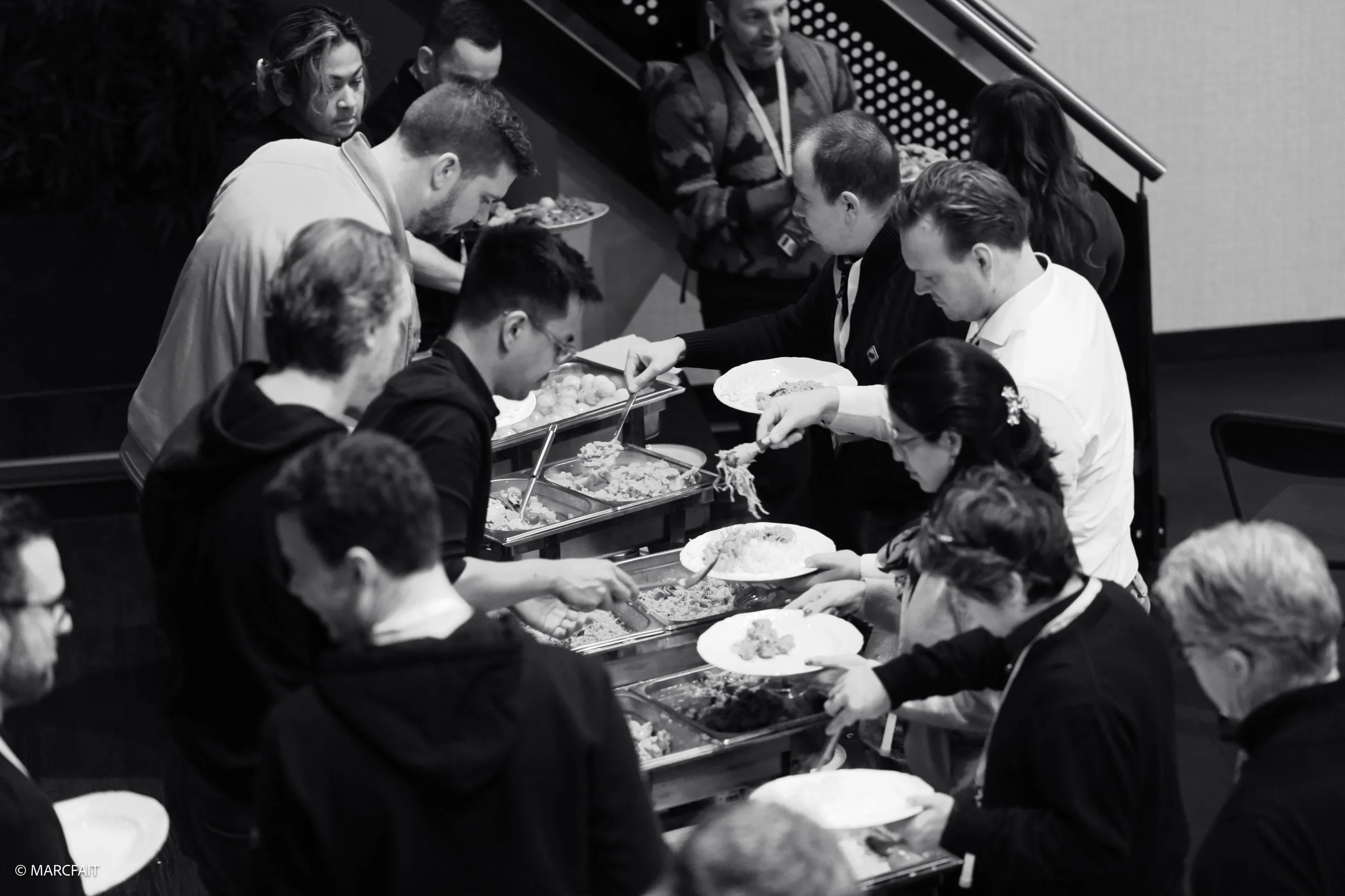 People serving themselves food at an Indonesian buffet in black and white.