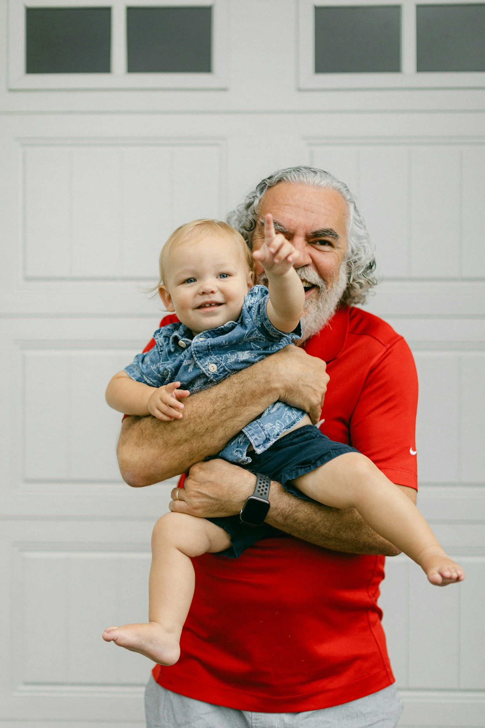 Grandpa with red shirt holding a pointing grandchild with a denim shirt