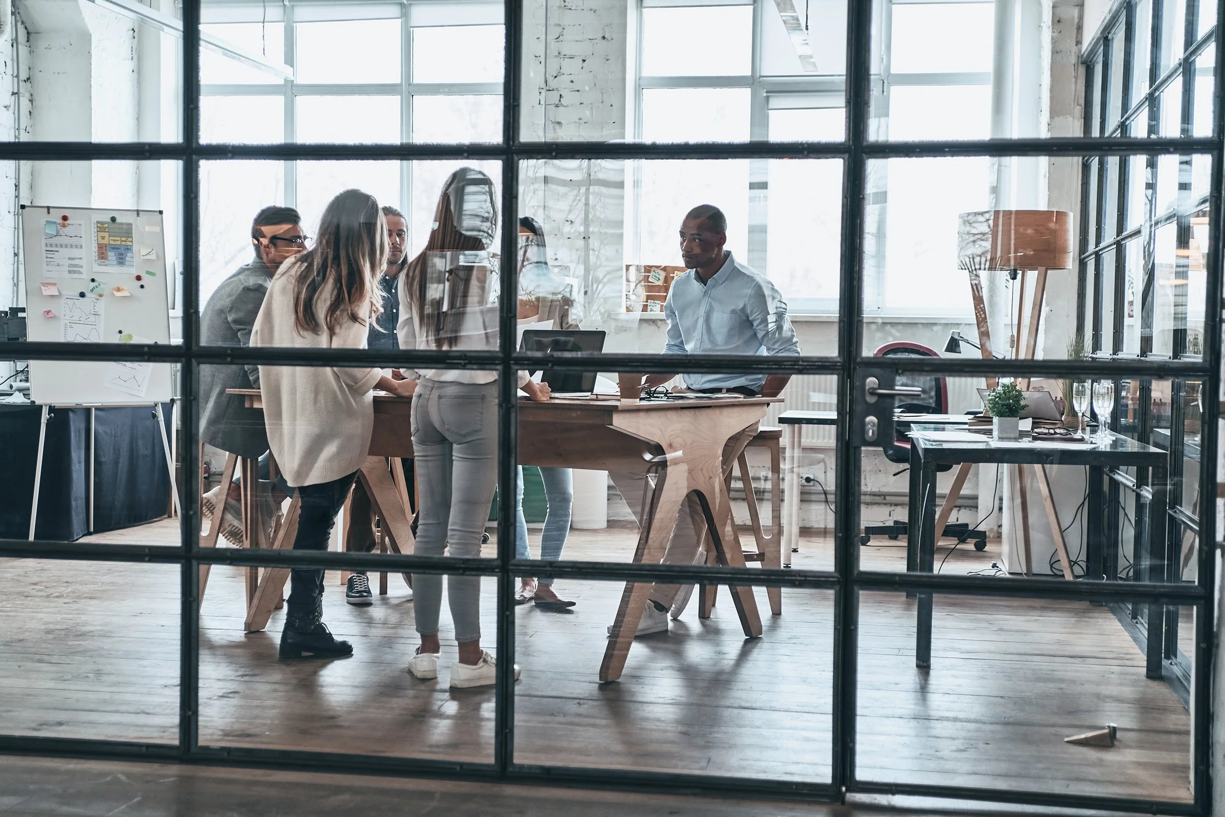 A group of people having a meeting in a modern office seen through glass office partition