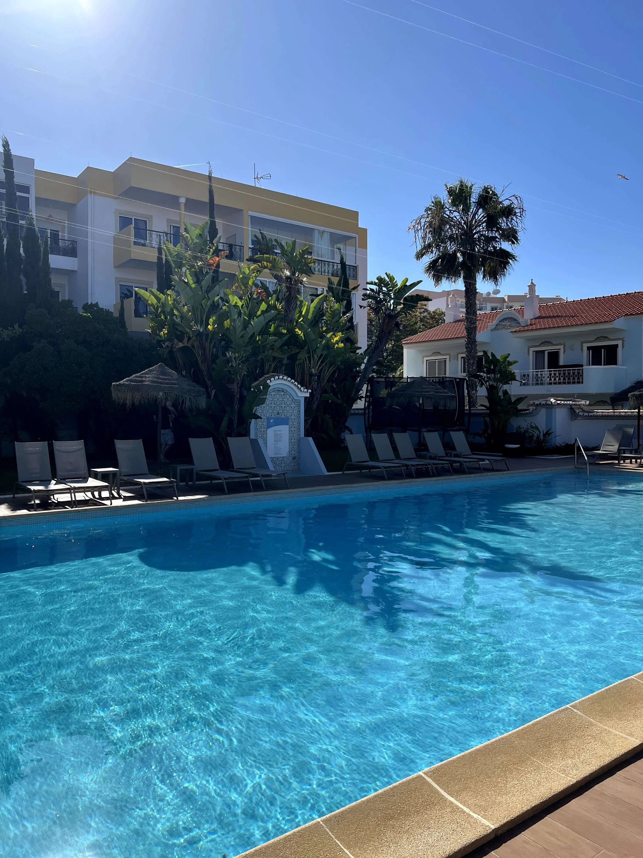 Swimming pool with sunbeds and palm trees at Casbah Lagos on a sunny day