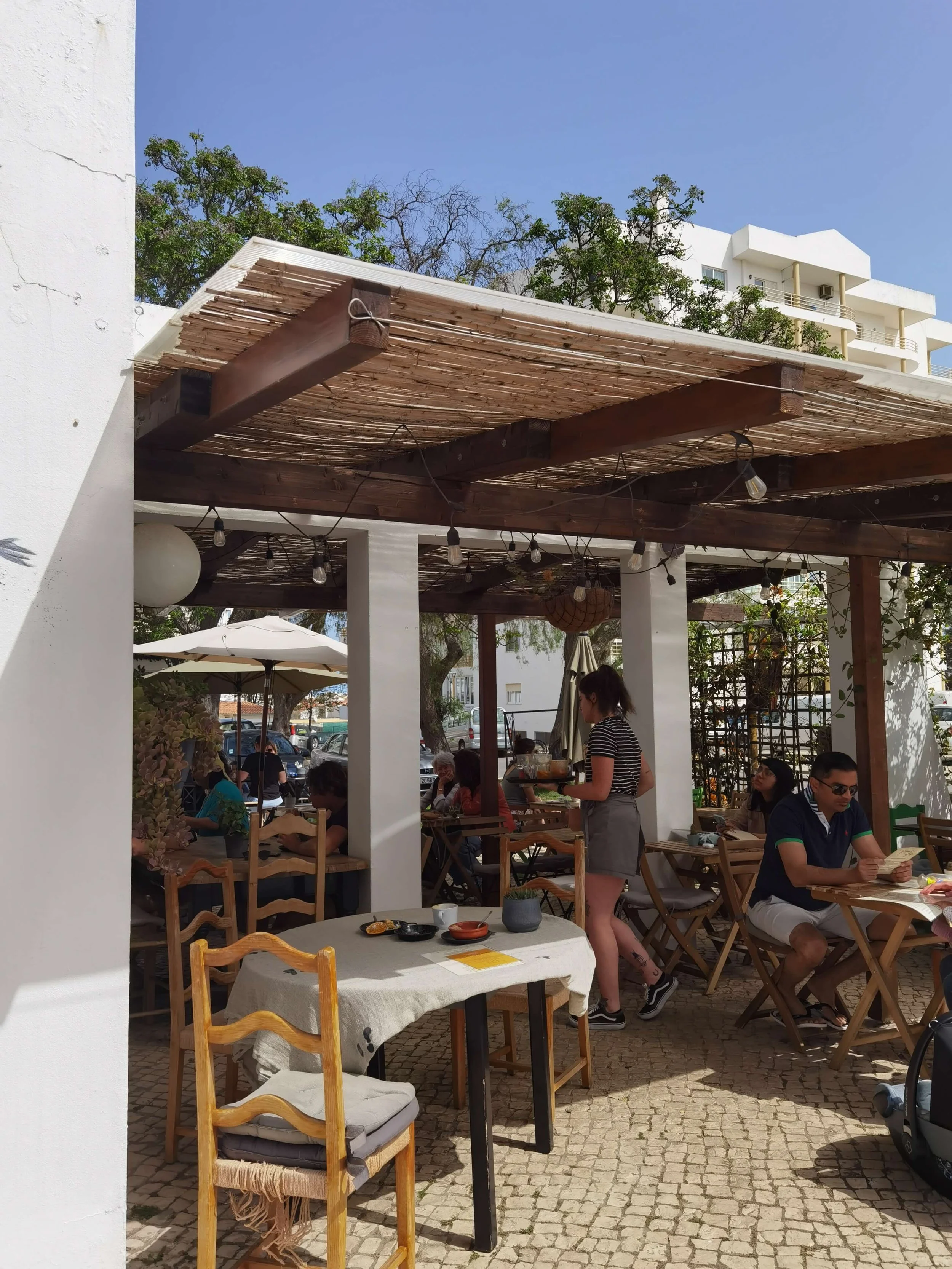 Shaded outdoor terrace with wooden tables at Sunrays Kitchen Lagos