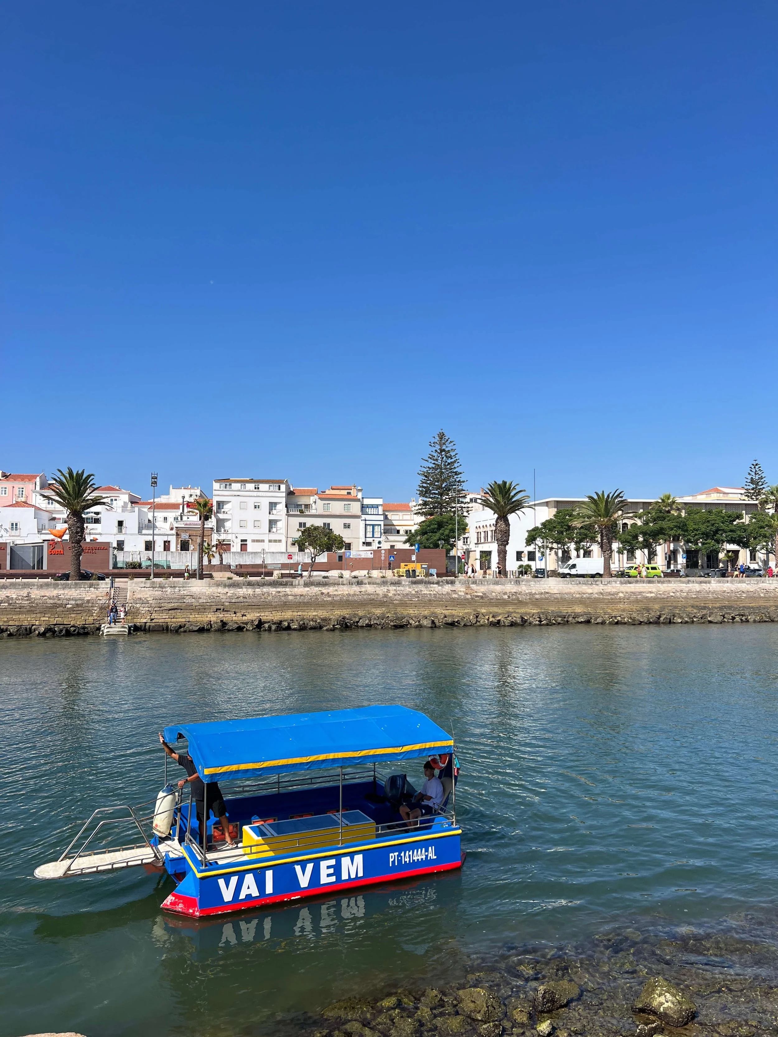 Vai Vem ferry boat crossing the water with Lagos old town and palm trees in the background