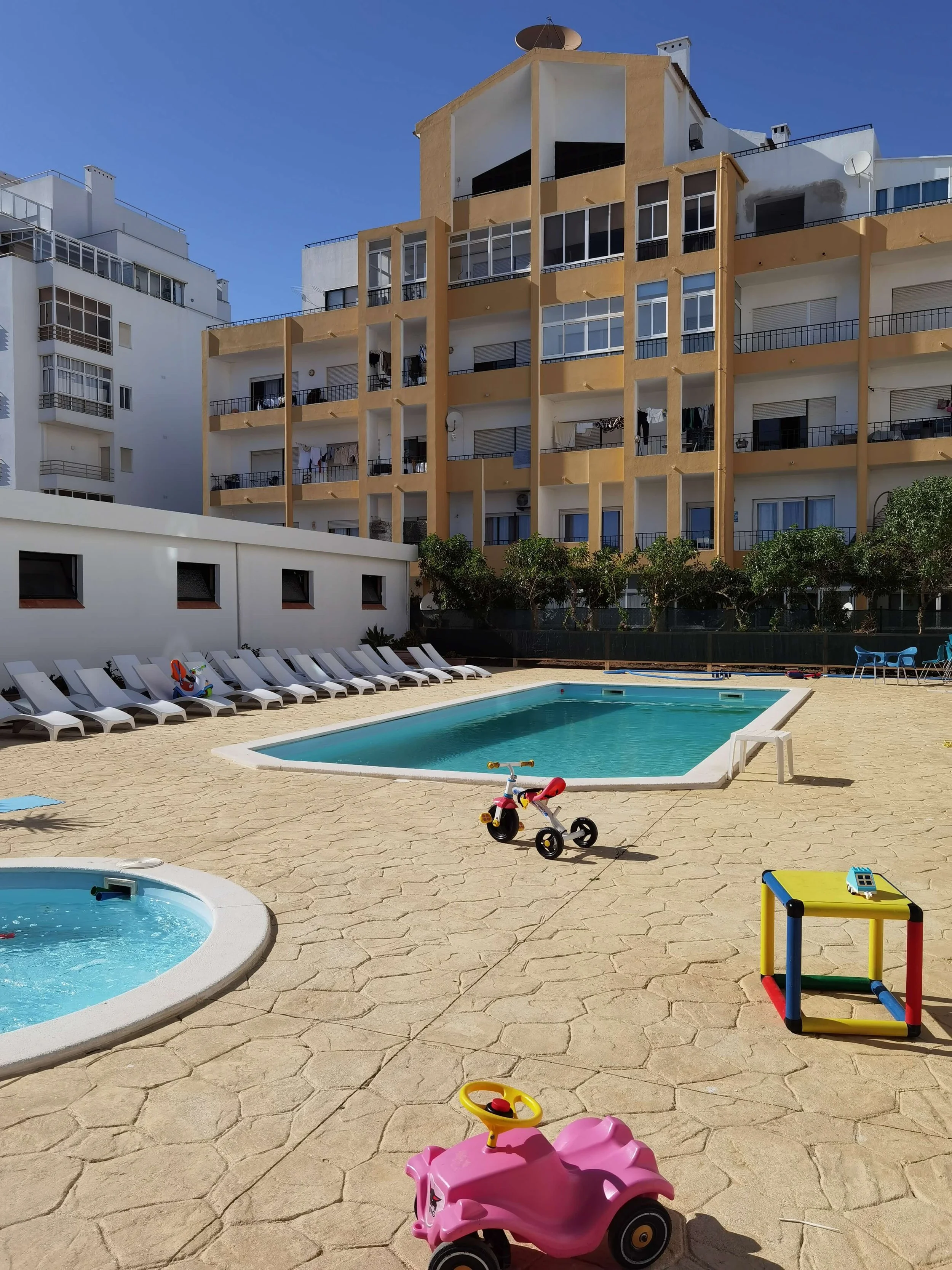 Sun loungers around the family pool with toddler pool and ride-on toys at Piscina Via Dona Ana Lagos