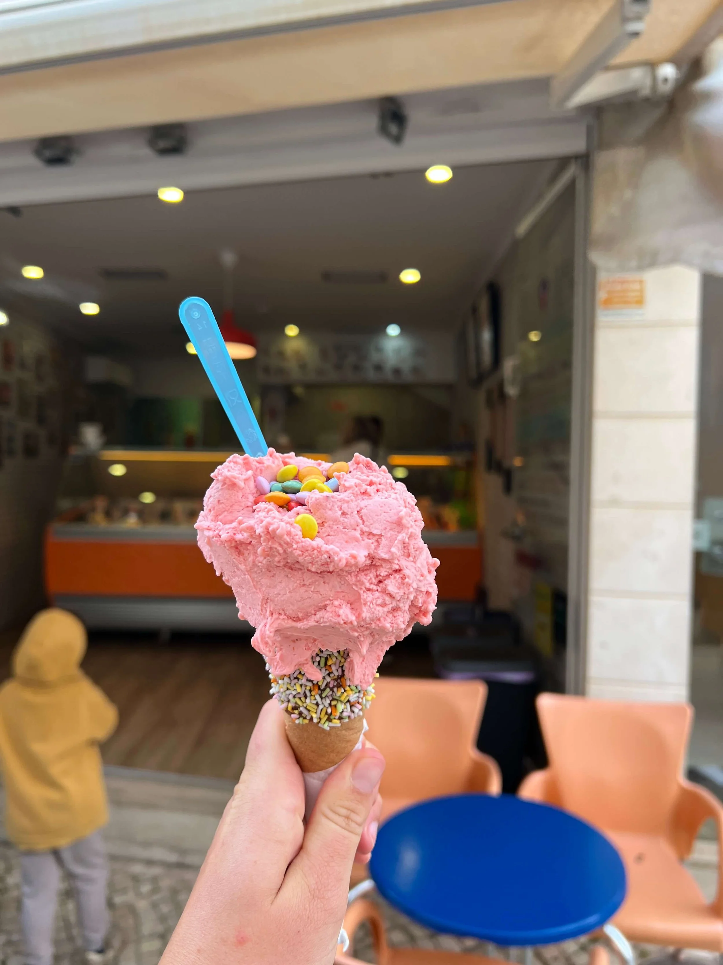 Pink ice cream cone with sprinkles and candy toppings from Crema di Gelato Lagos