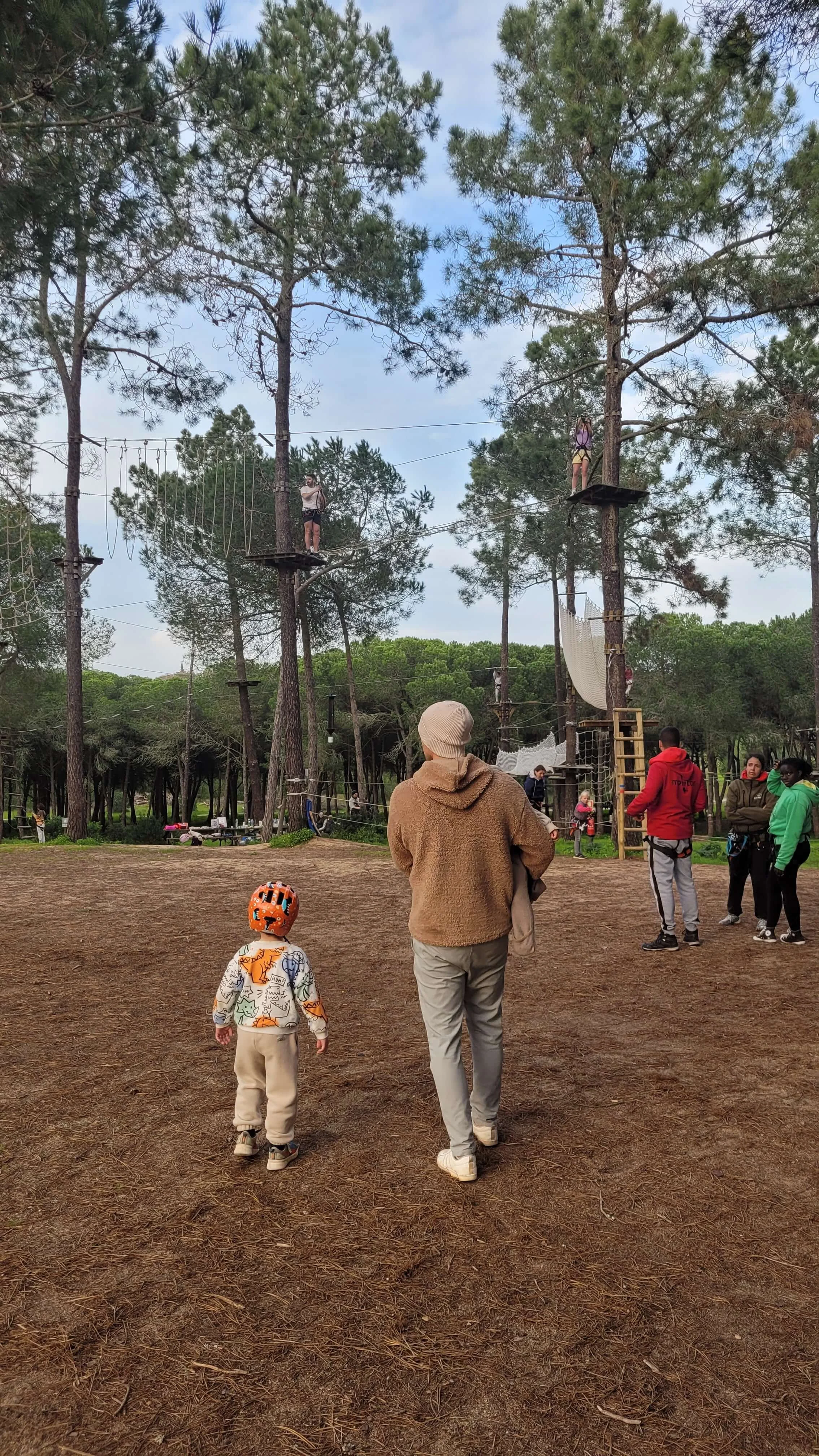 Father and child with helmet watching climbers in the treetops at Parque Aventura Lagos