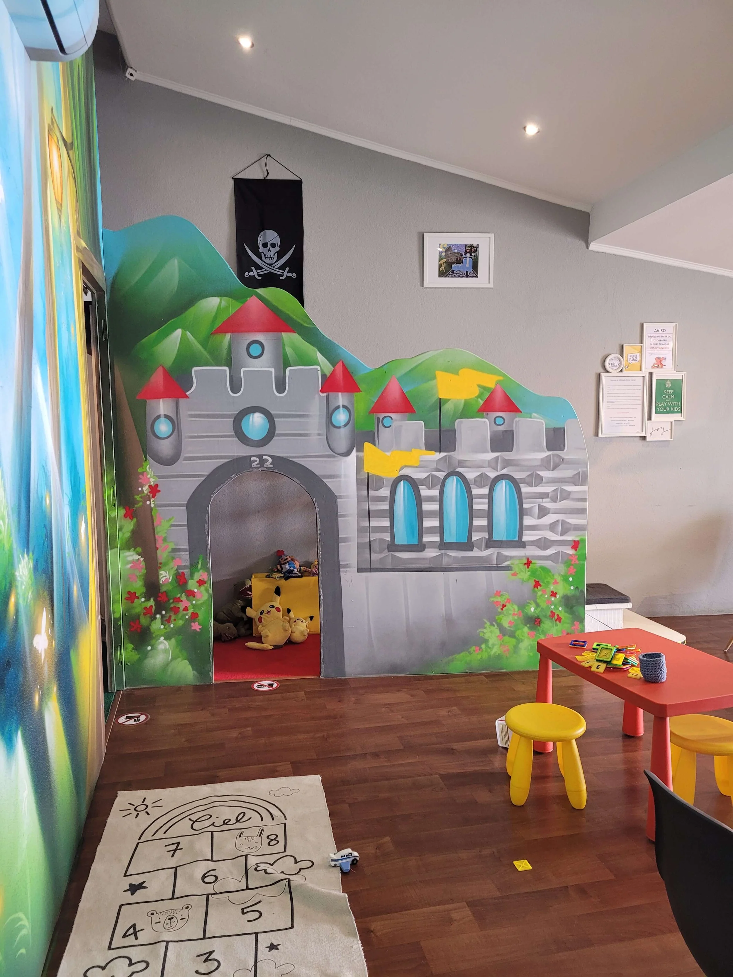 Castle play structure with pirate flag and hopscotch mat at O Ninho kids area Lagos