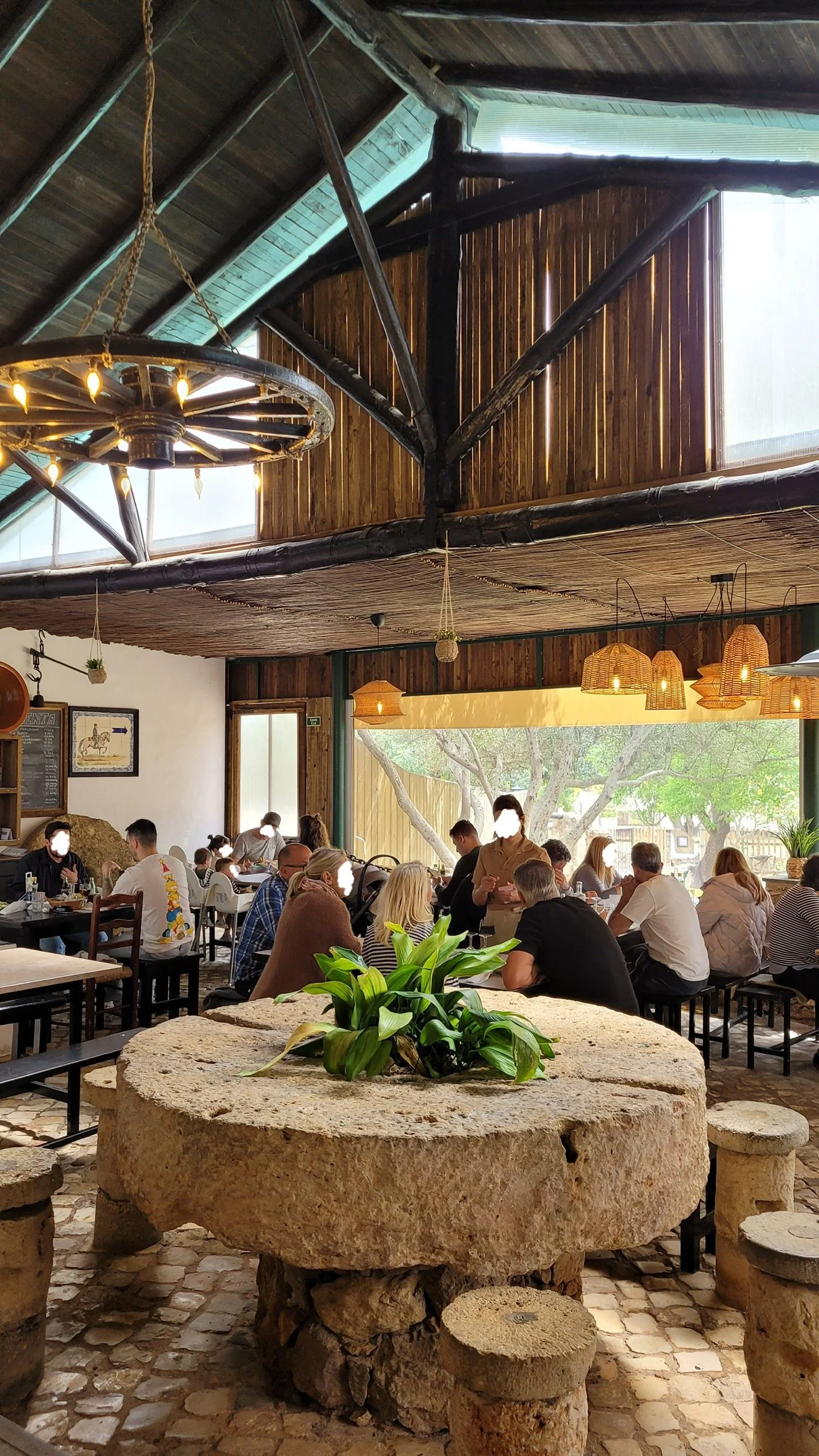Rustic barn-style dining room with stone millstone and wagon wheel chandelier at Casa Chico Ze near Lagos