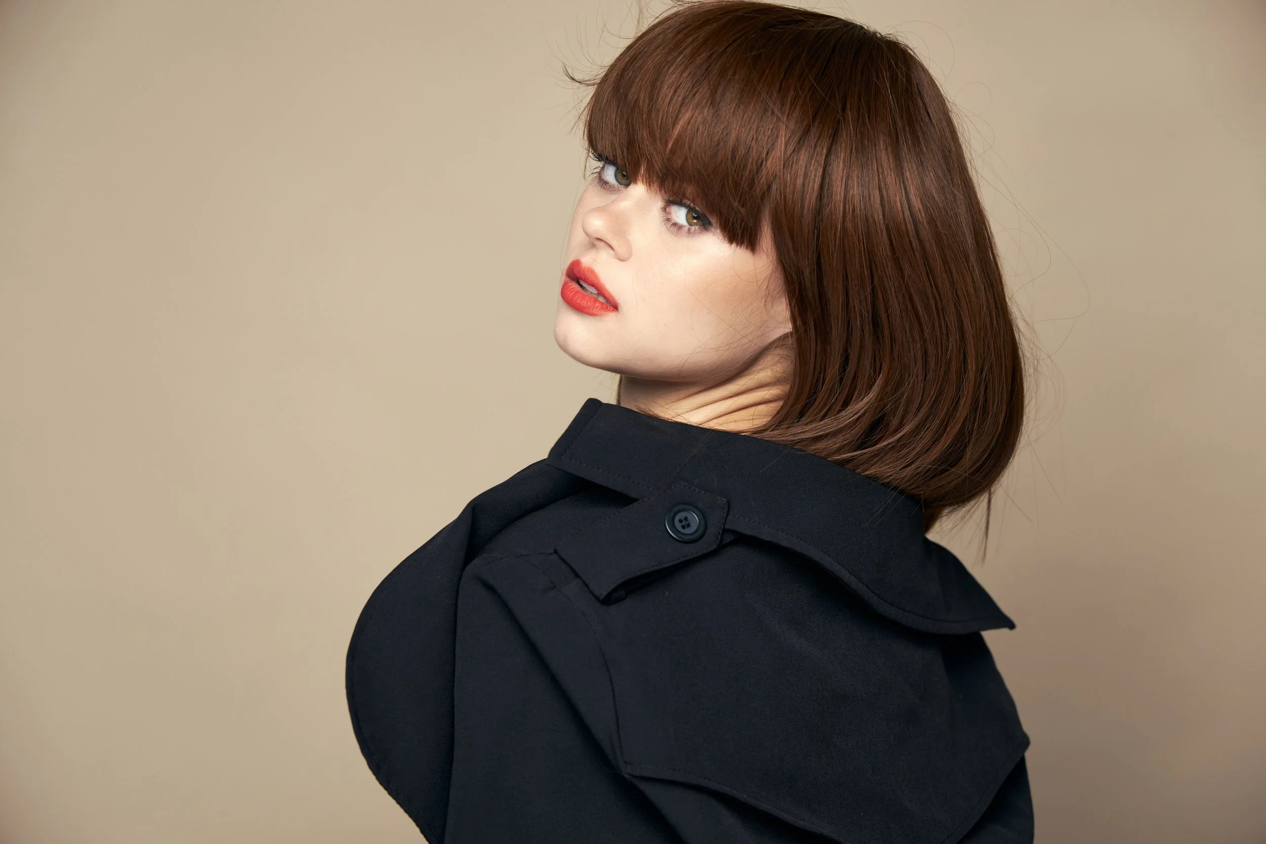 A luxurious brunette with full shoulder length hair cut in a sharp bob with bangs