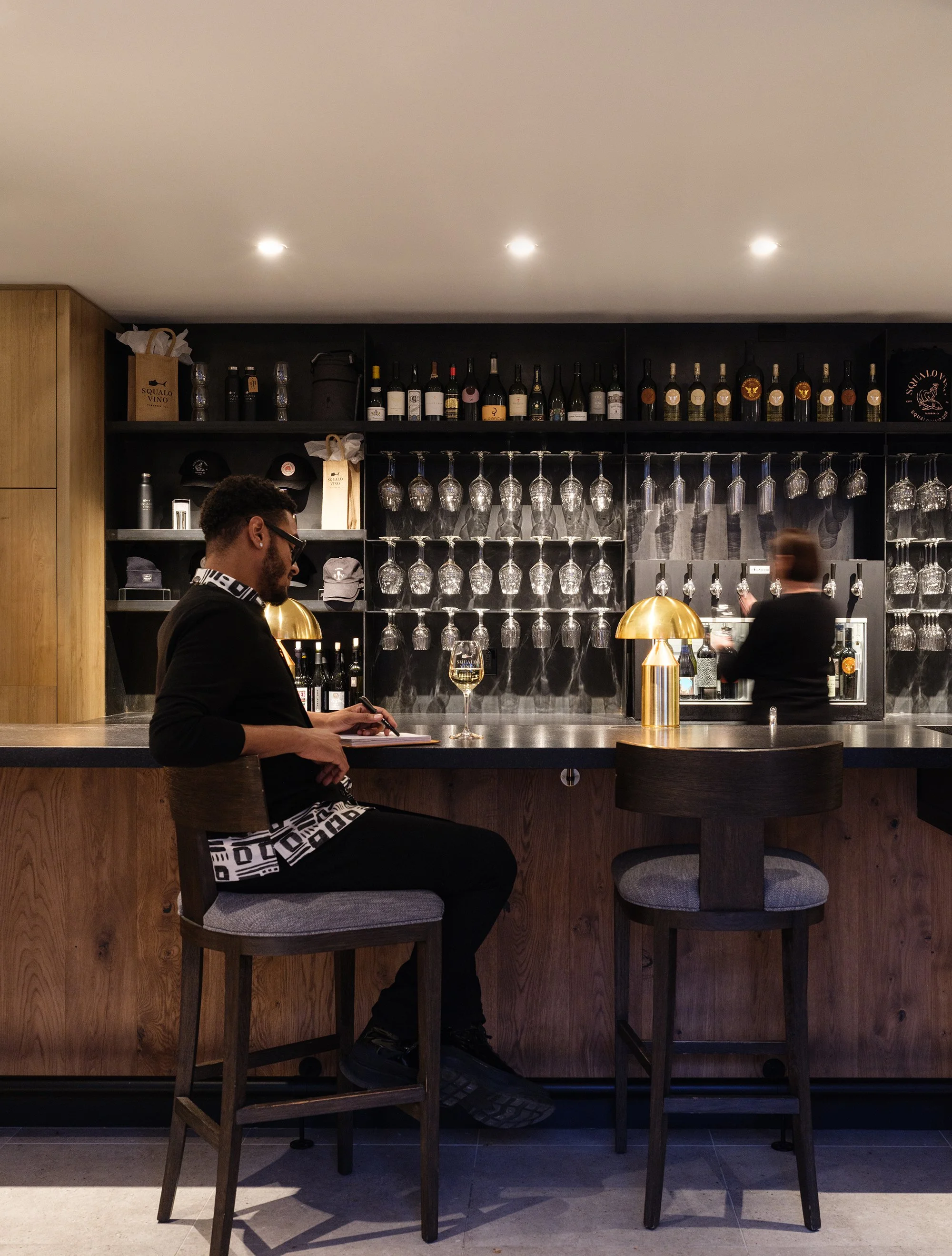 Custom bar design at Squalo Vino wine bar featuring industrial steel, brass, and stone materials in Tiburon