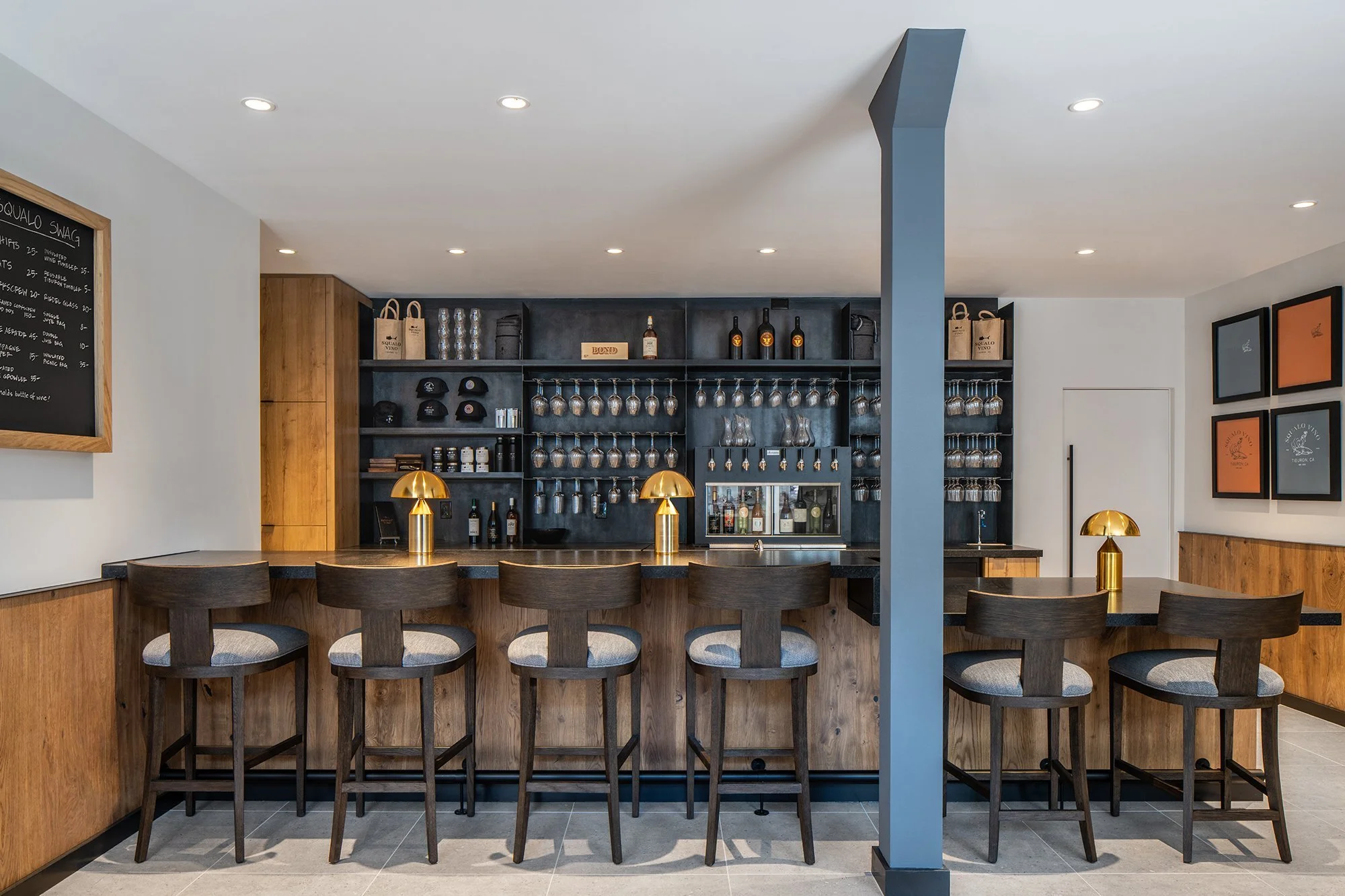 Main interior of Squalo Vino wine bar showing warm multi-toned woods, brass lamps for a moody and modern wine bar design in downtown Tiburon