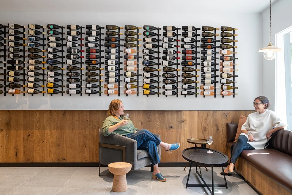 Main interior lounge of Squalo Vino wine bar showing warm multi-toned wood, mobile Vitra stools, and modern wine bar design in downtown Tiburon