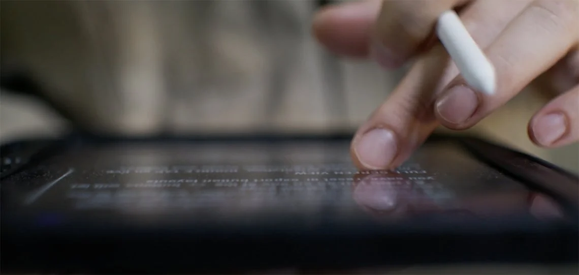 Close up image of a person using a tablet with their finger
