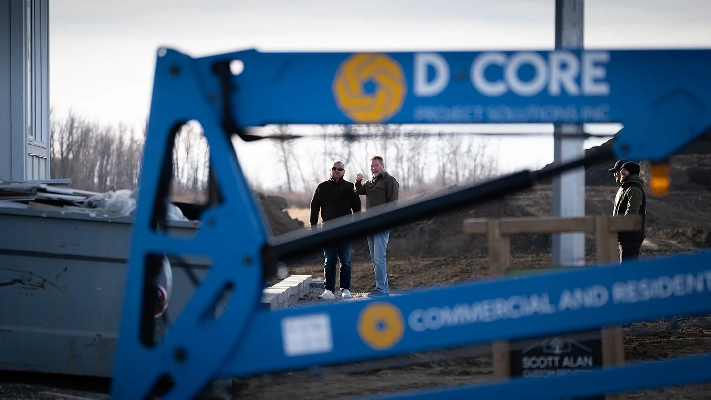 Image of empty lot with construction equipment in the foreground and two people having a conversation in the background