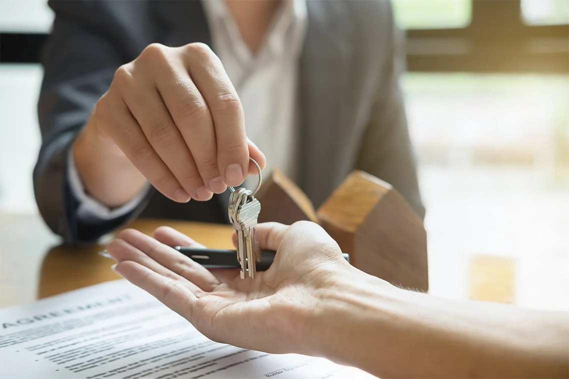Image of keys being handed from one person to another