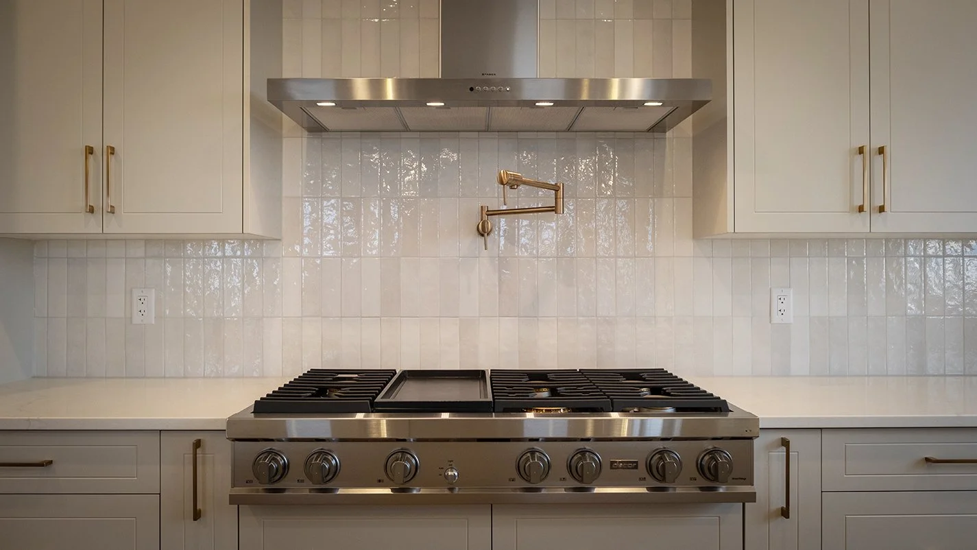 Image of a gas top stove, thin profile extractor hood, cabinets and splash-back