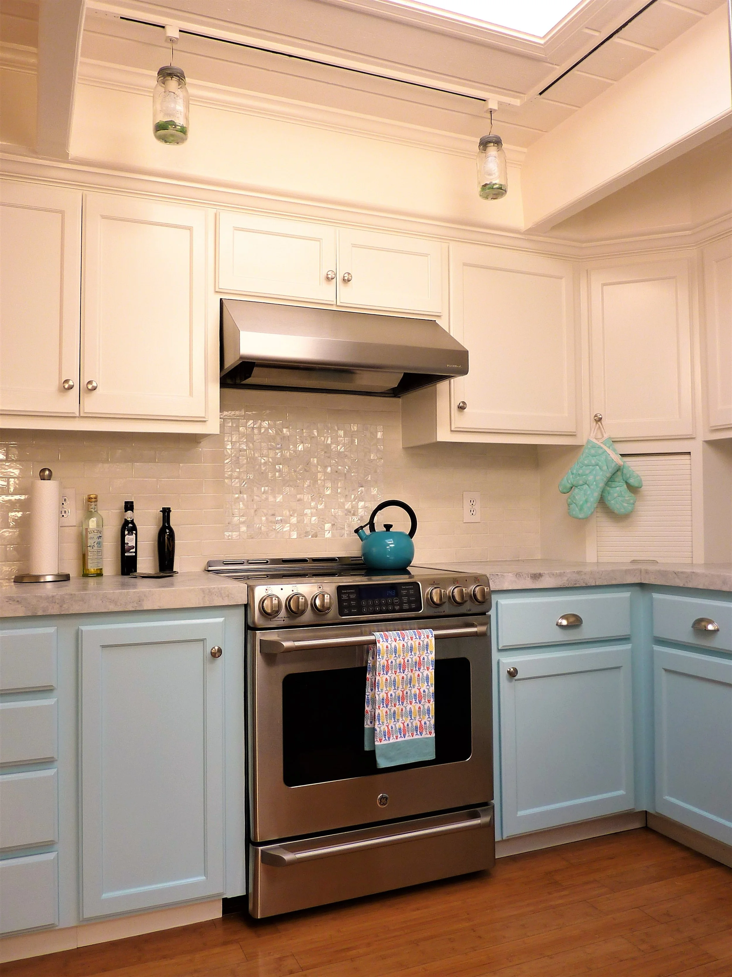 A vertical image of the oven and surrounding counterspace and cabinetry are brightened by the natural light from the skylight overhead.