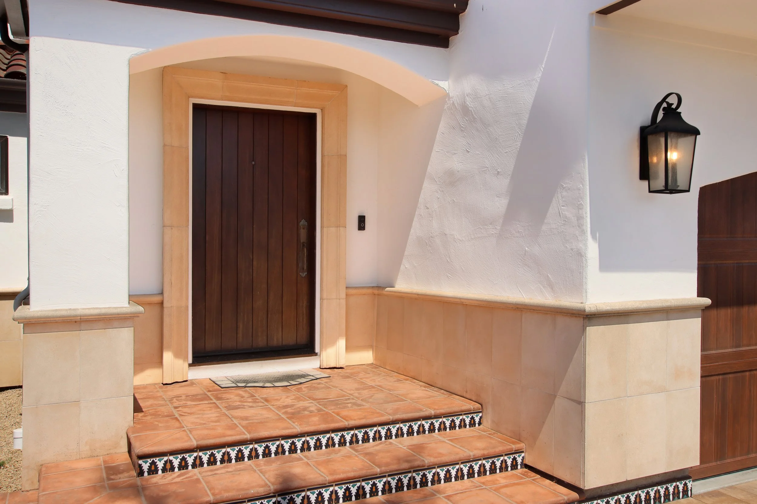 Classic spanish architecture with stucco exterior, tile front steps, and painted tile edging.