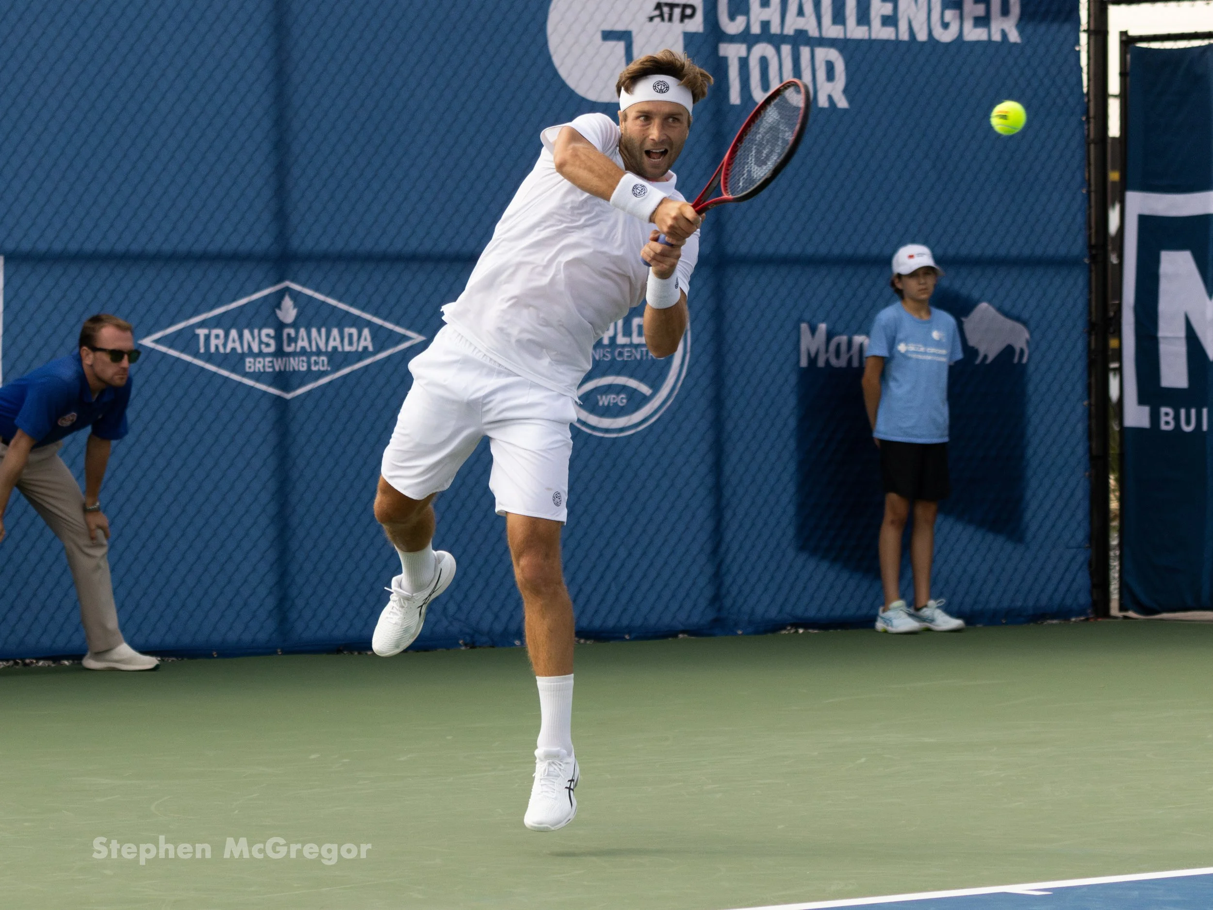 Liam Broady hits a tennis ball with a backhand stroke during a tennis match.