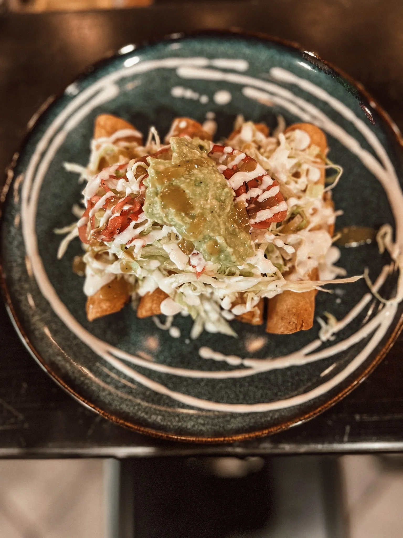 Taco plate with chopped cabbage, guacamole, salsa, sour cream, and fried taco shells on a dark plate.