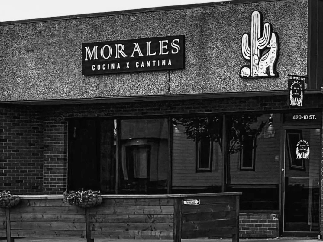 Sign for Morales Cocina y Cantina restaurant with cactus and cat illustrations on the wall.