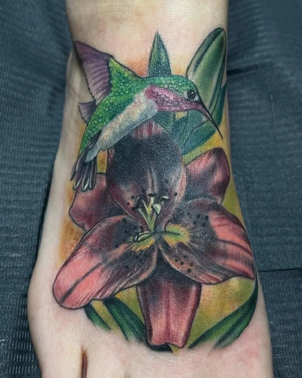 Color hummingbird and lily tattoo coverup on a foot by Daniel Stewart at Signature Rose Professional Tattooing in Muncie Indiana.