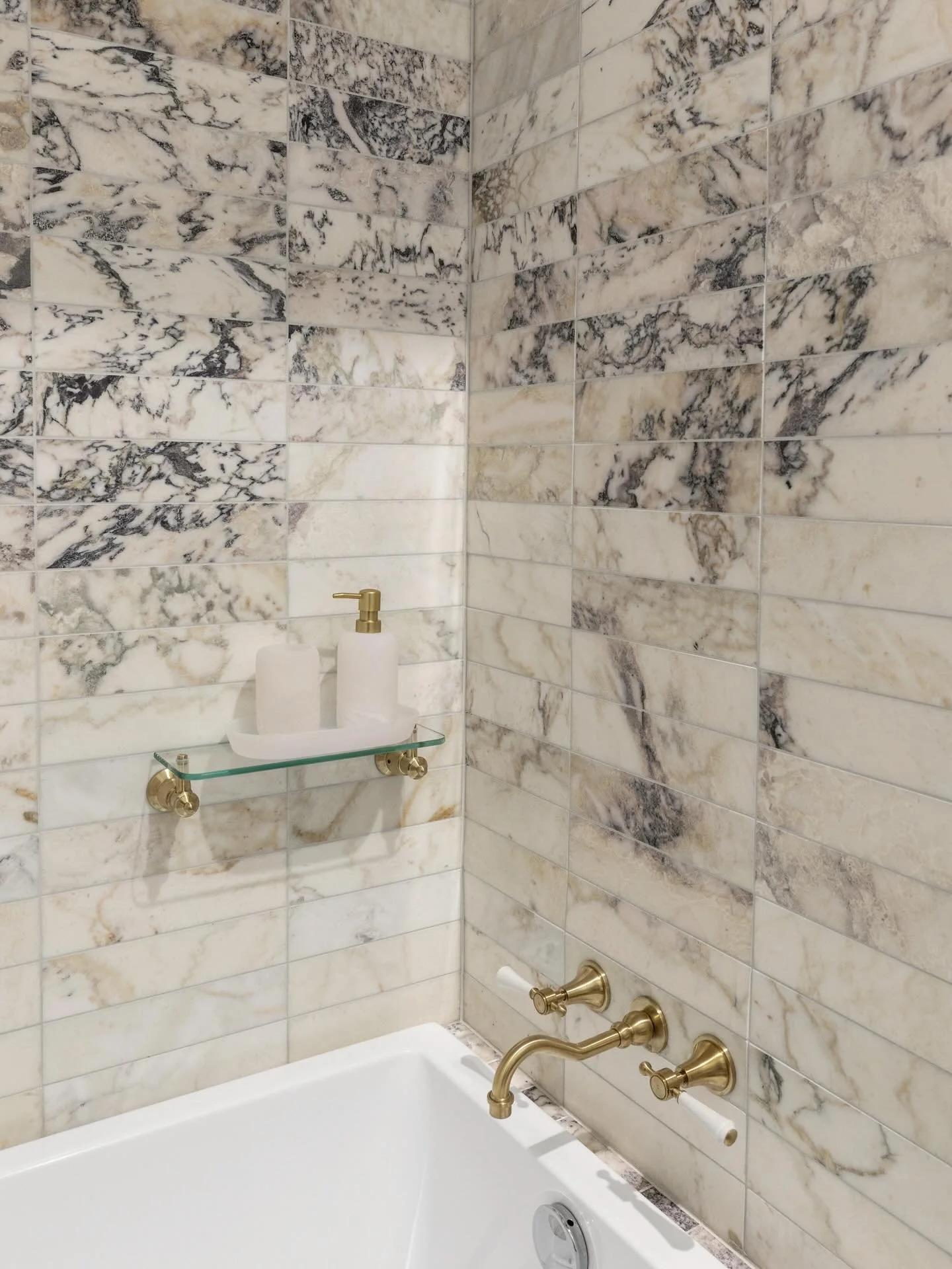 Tile placement was considered as carefully as the selection itself. These natural marble tiles carry a spectrum of purples, creams, golds, whites and greys, and by grouping the darker pieces together, the variation becomes more pronounced, creating d