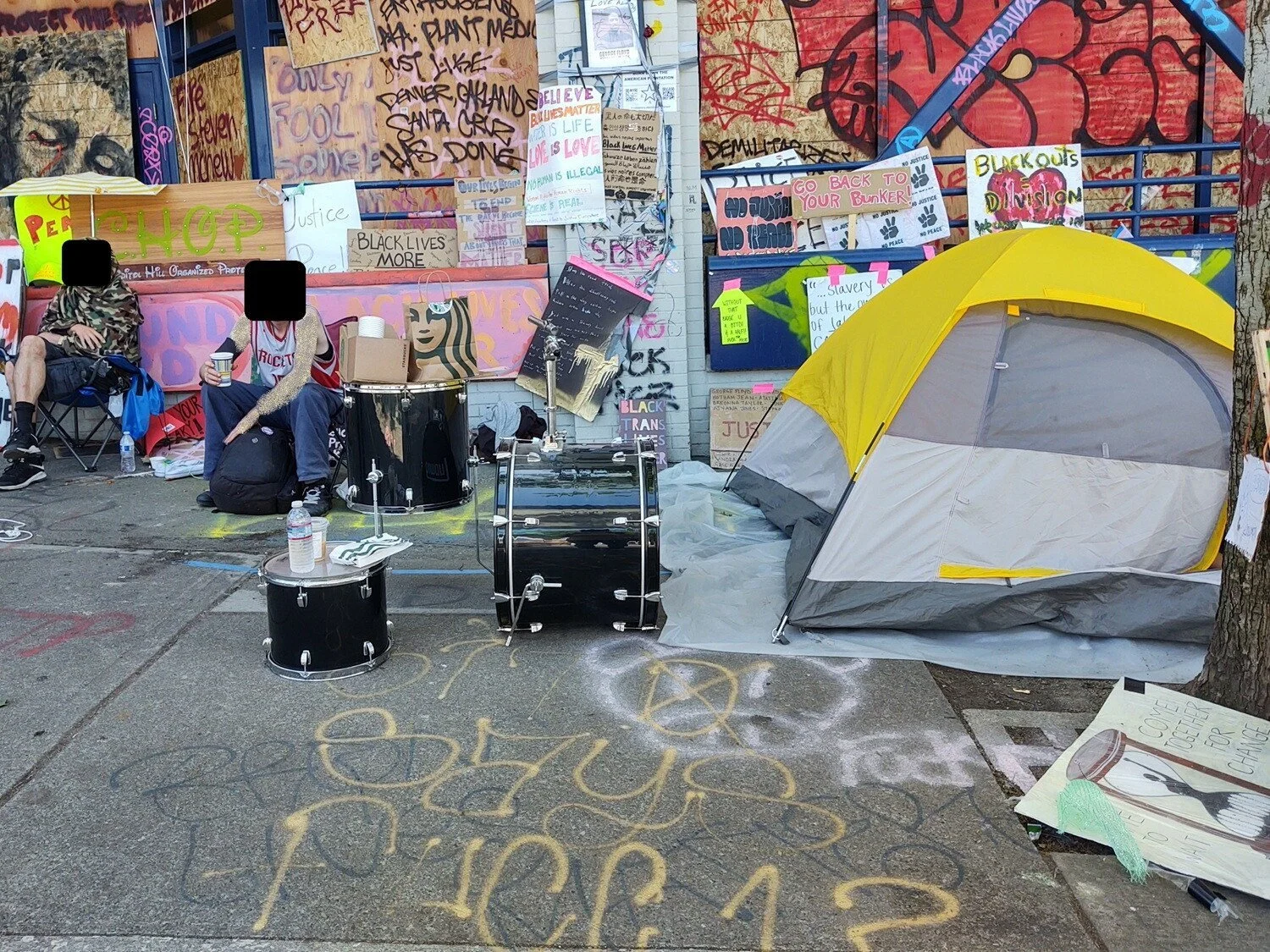 People sit near a drumset outside the precinct.