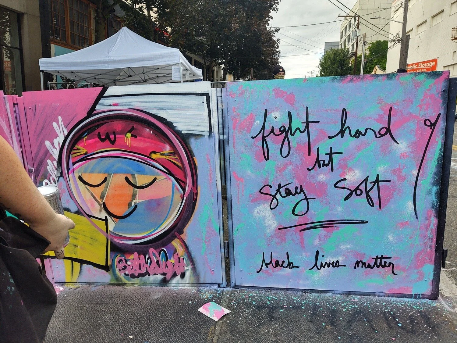 Painting reads "fight hard but stay soft" and "black lives matter". Abstract blue and purple background with black letters.