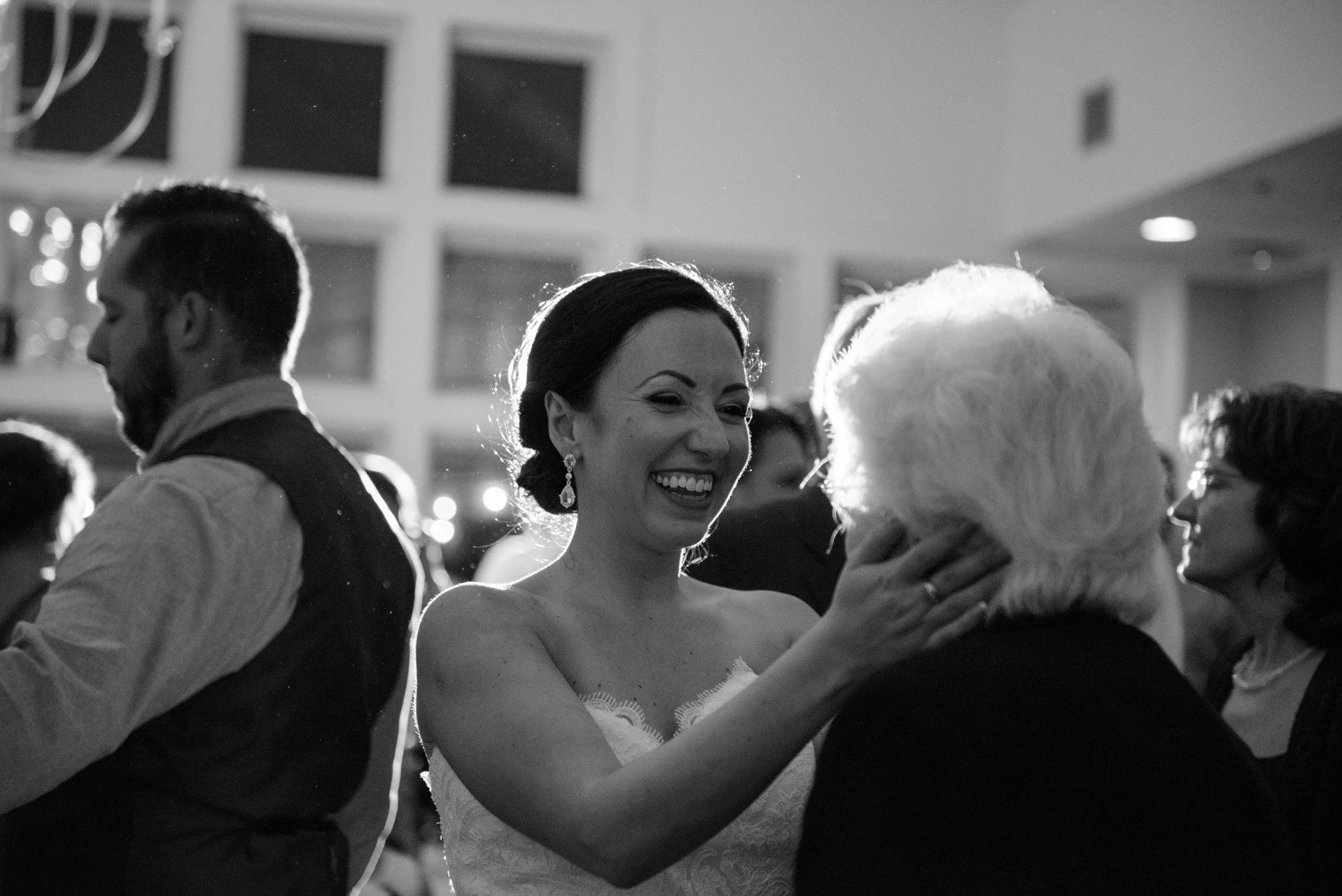 new-england-wedding-photographer-reception-candid-bride-hugging-guest-black-and-white-004.jpg