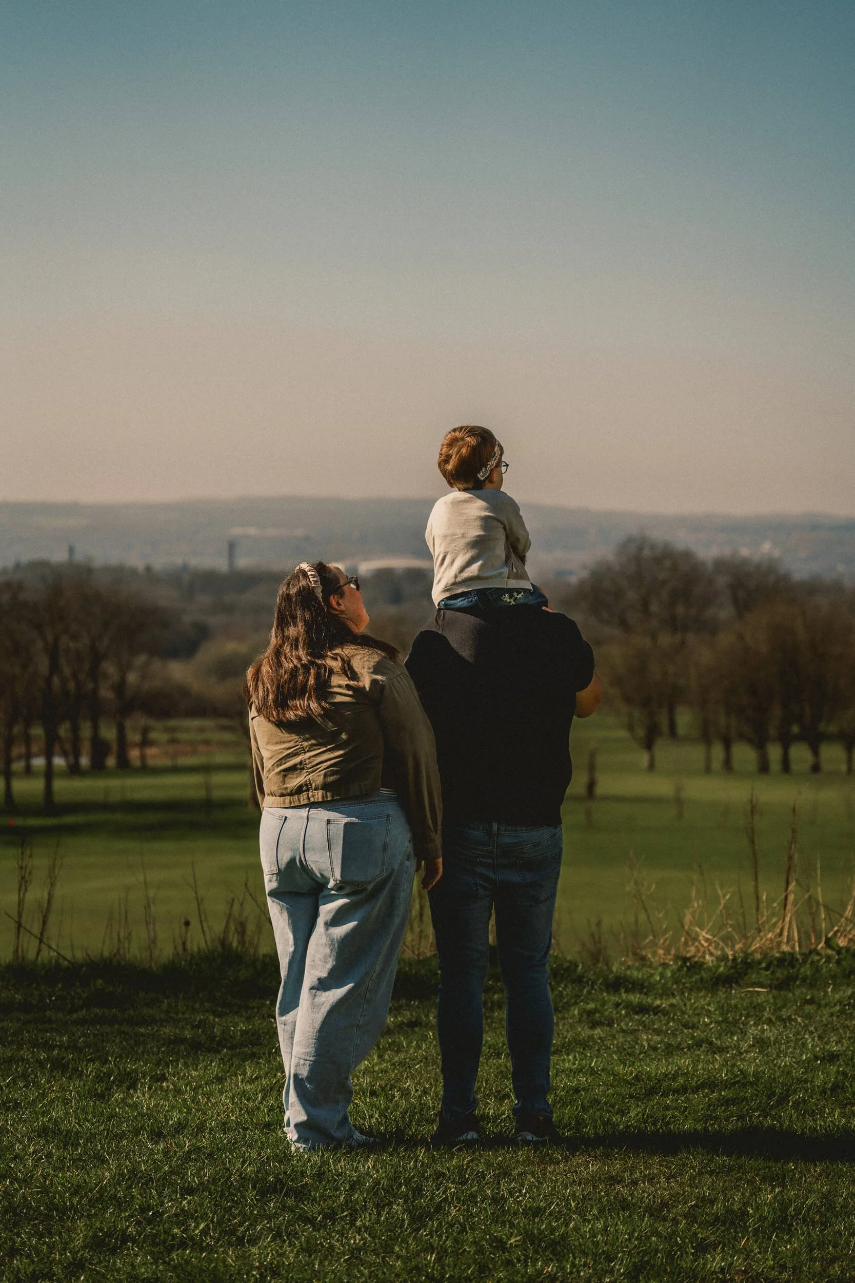 Family standing together and looking across the countryside at Haigh Woodland Park in Wigan.