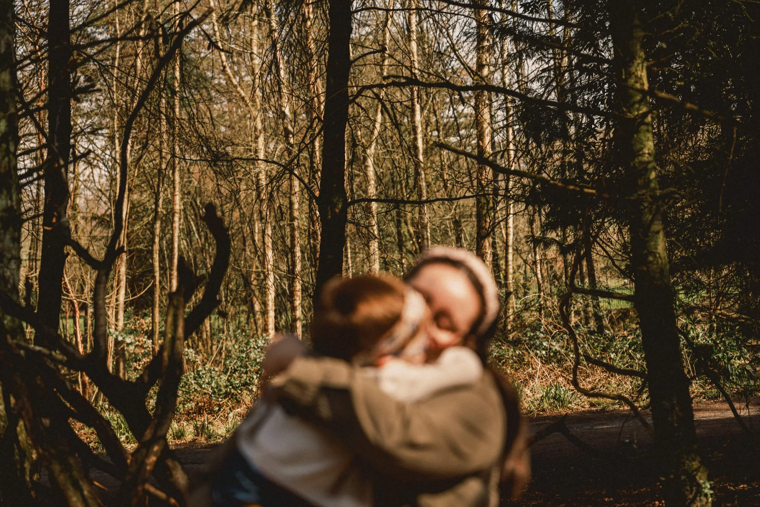 Child sharing an affectionate moment with a parent during a family day at Haigh Woodland Park in Wigan.