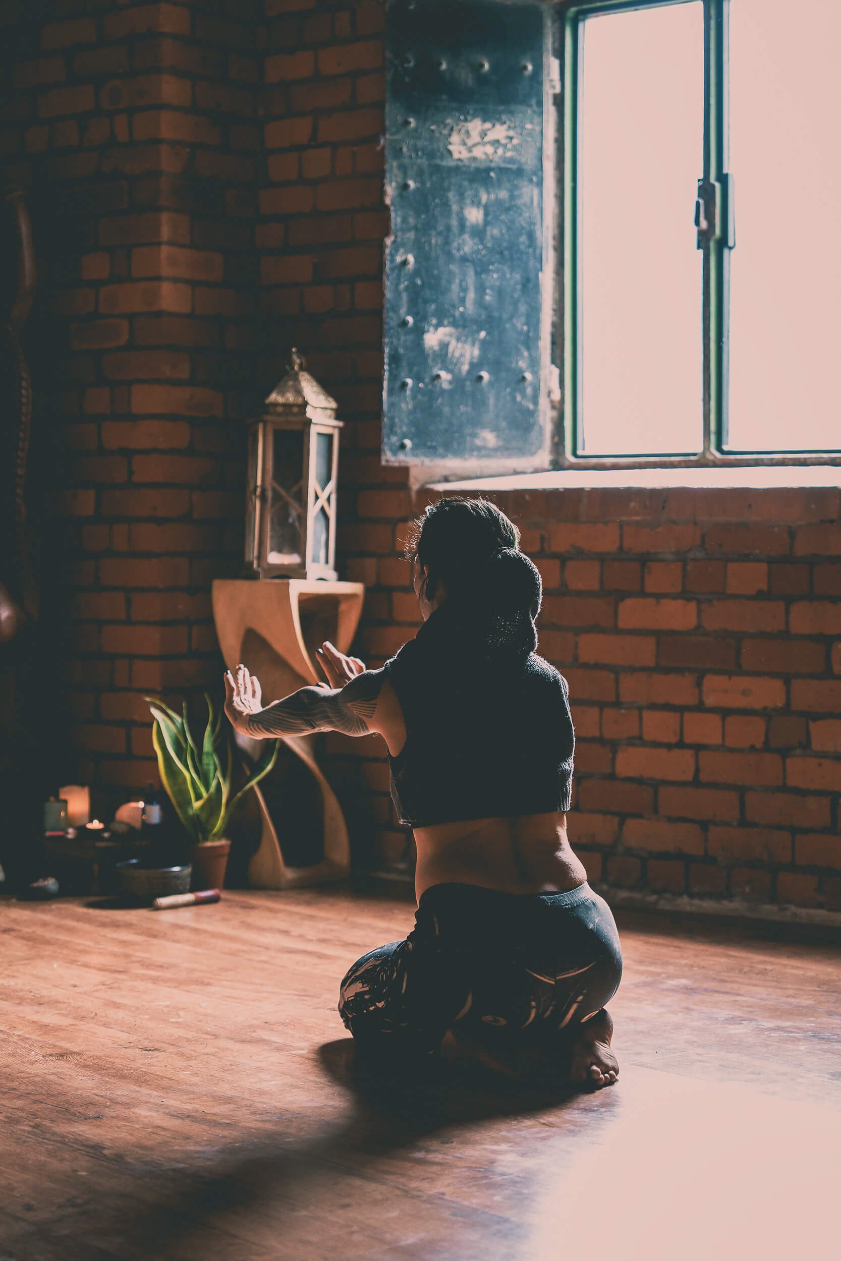 Participant kneeling on a yoga mat during a yoga workshop, practising a movement exercise in a brick studio.