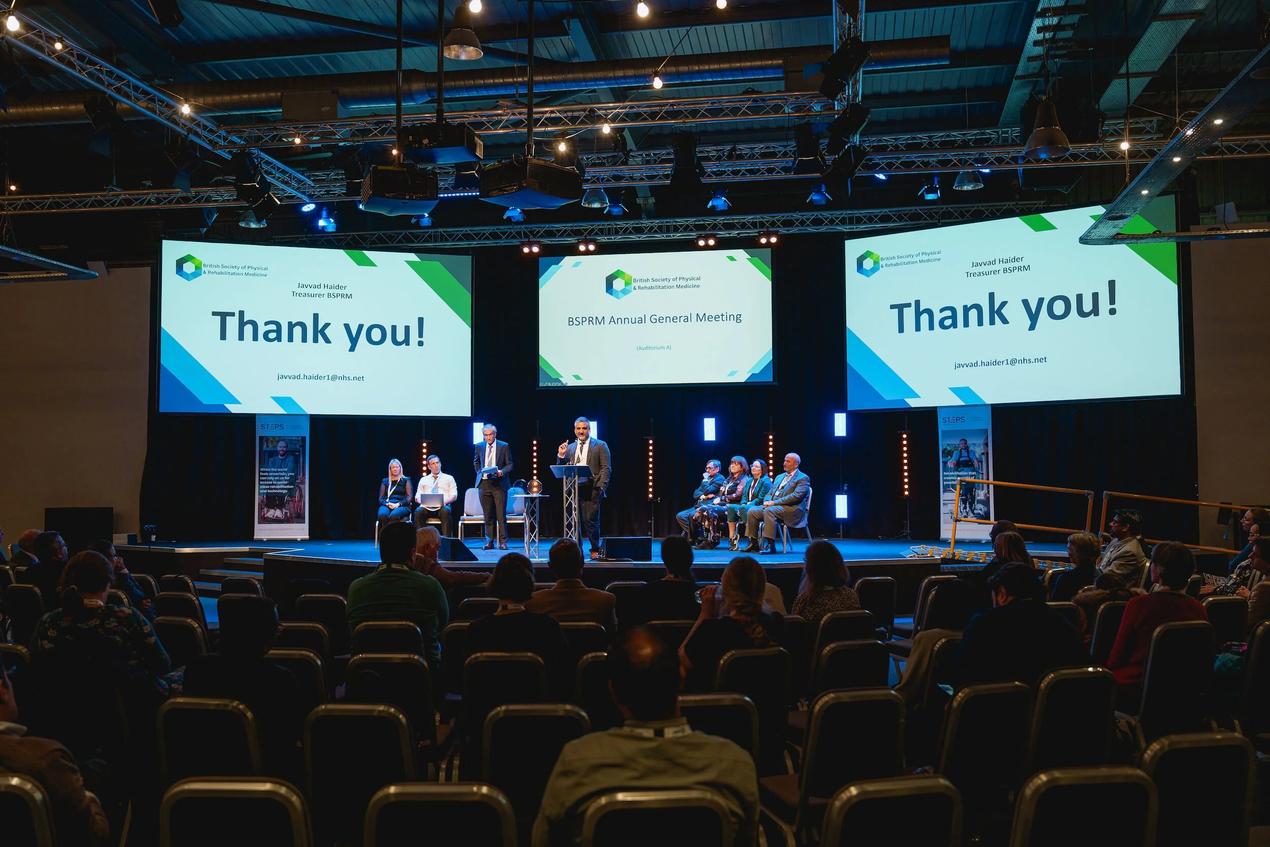 Wide view of a conference stage and audience during the closing session.