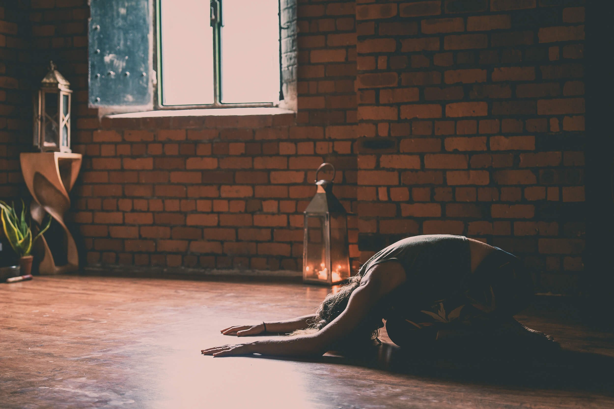 Participant stretching on the floor during a yoga and wellbeing workshop, with warm natural light filling the studio.