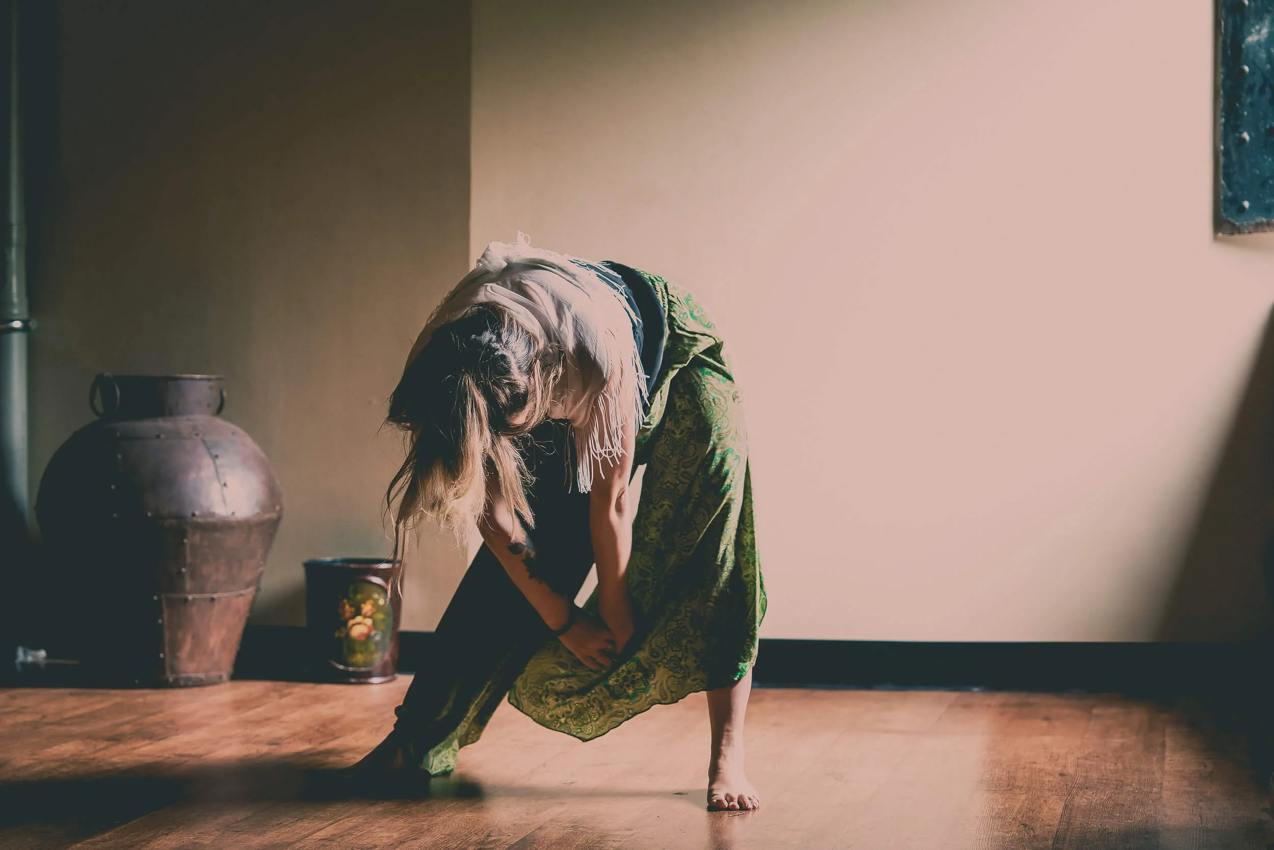 Participant practising yoga during a wellbeing workshop in a sunlit studio, surrounded by wooden floors and textured walls.