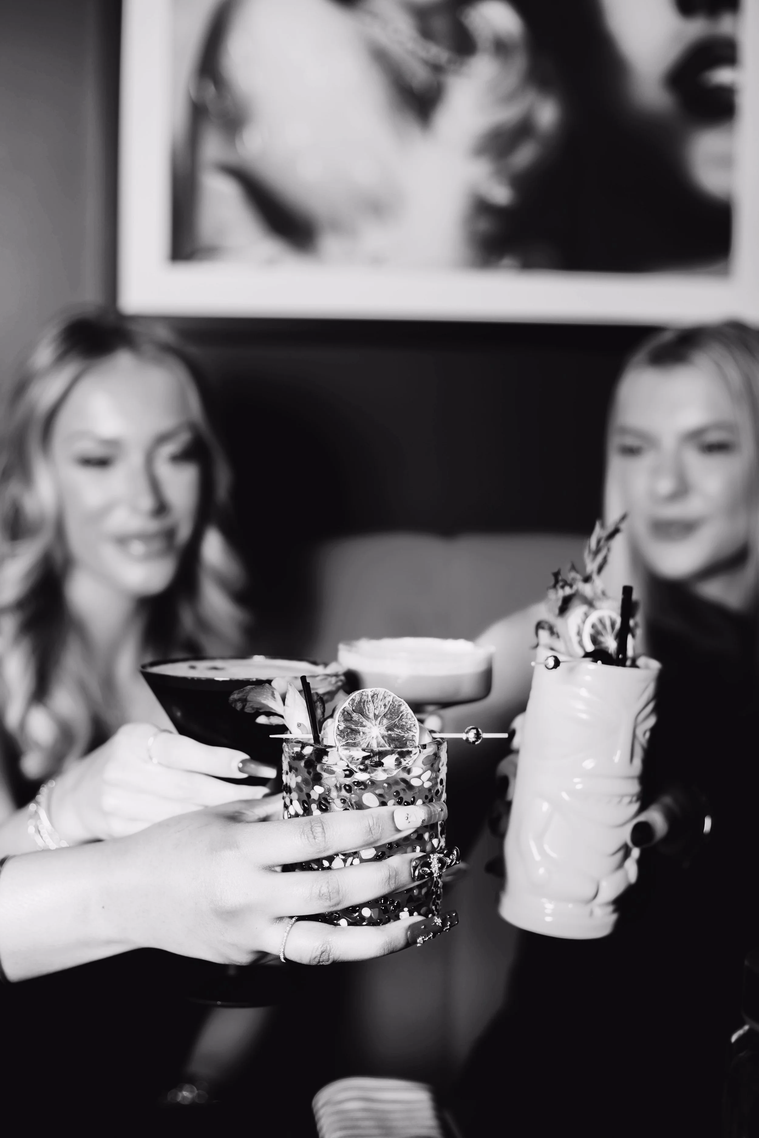 A group of women clinking cocktail glasses together at a table inside Silk Utica, a cocktail and dessert bar in Utica, NY, enjoying a night out.