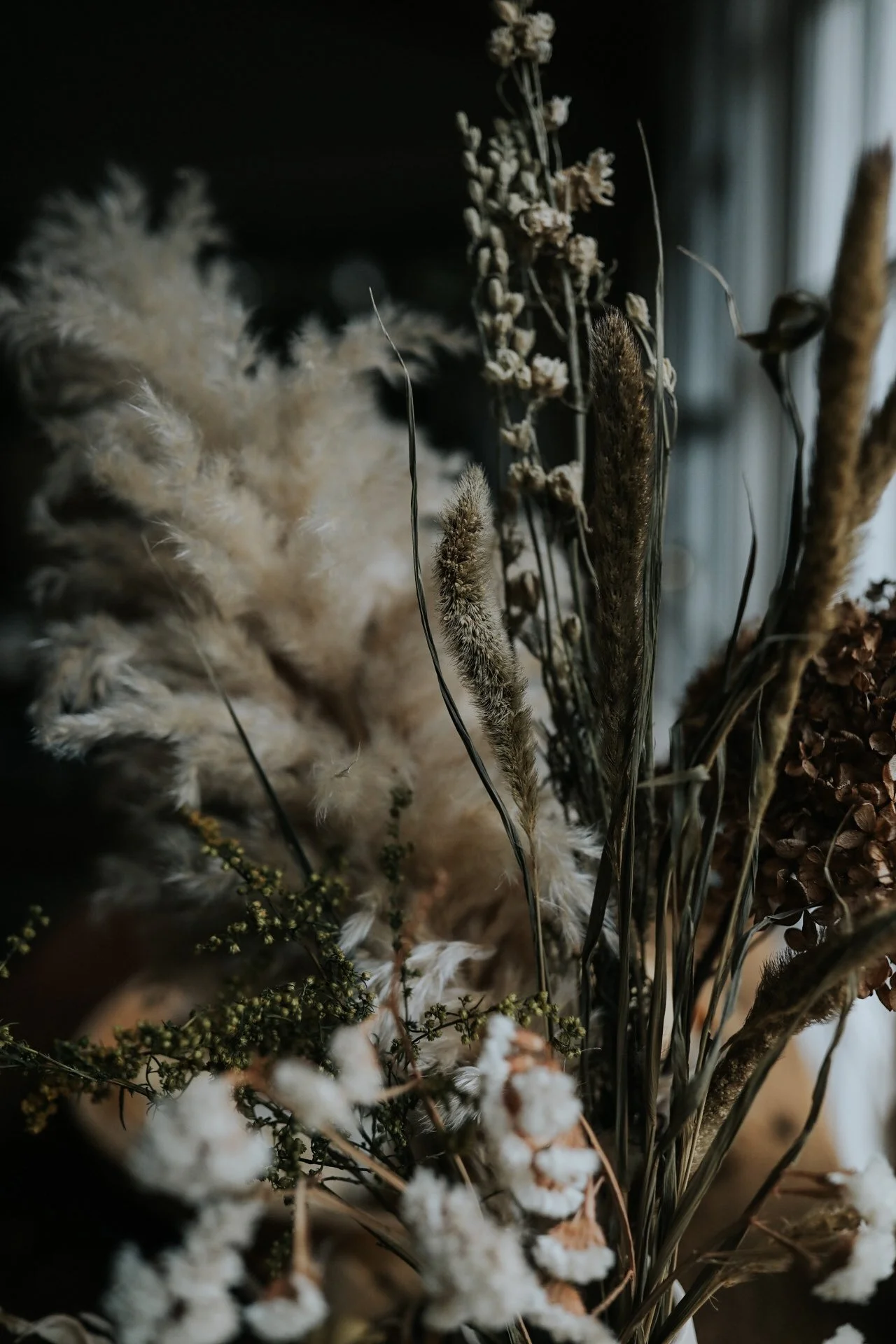 Close-up of dried floral arrangement with pampas grass and various dried flowers in muted tones.